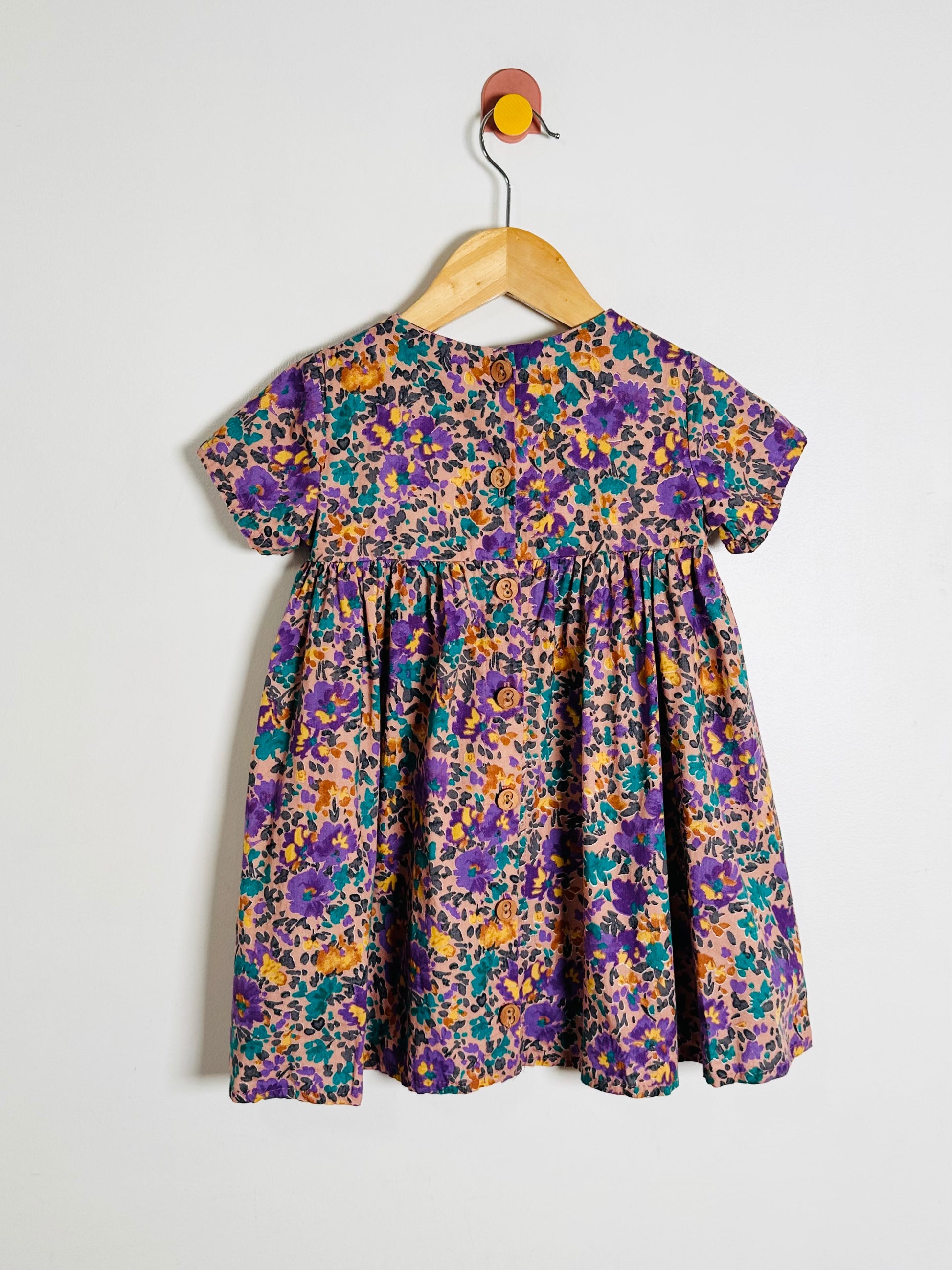 Floral dress on a hanger against a white background