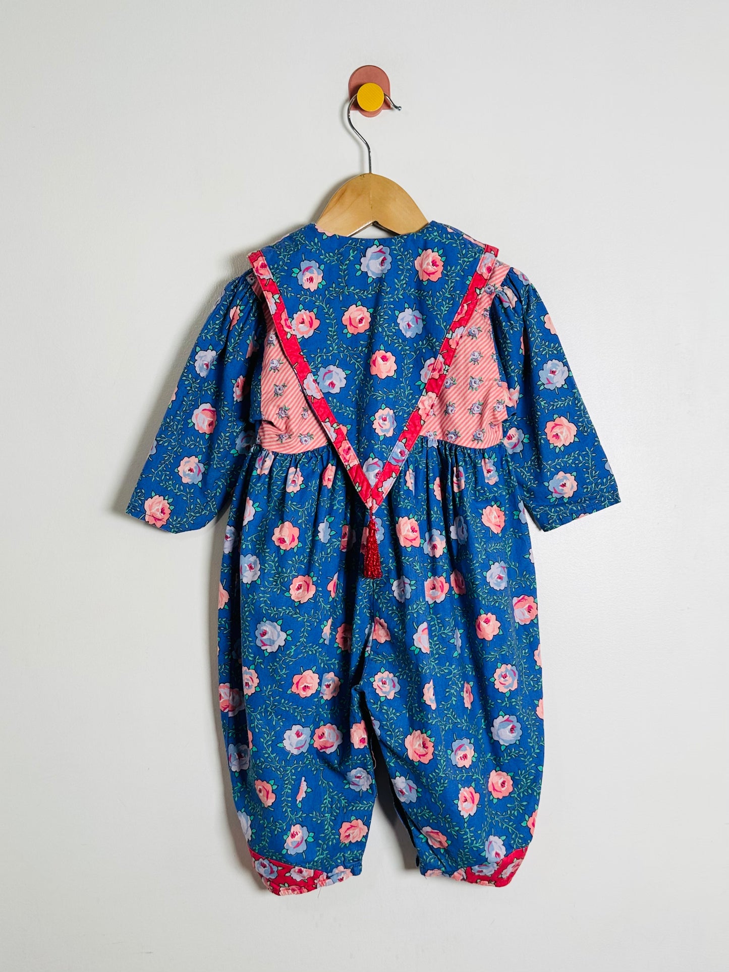 Children's blue floral romper with pink accents on a white background