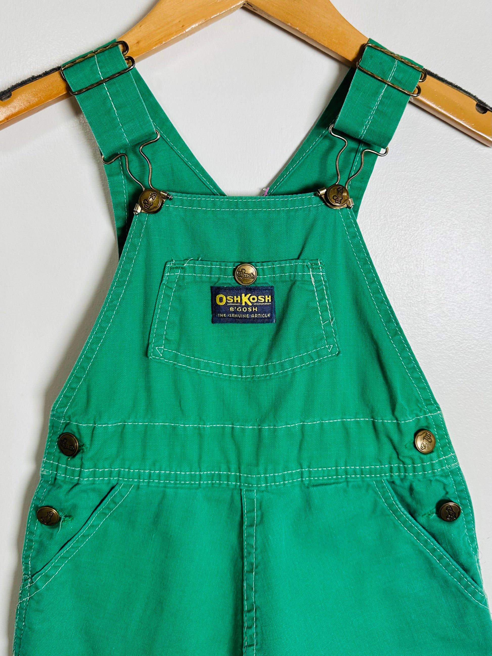 Green overalls with a visible brand label on a white background