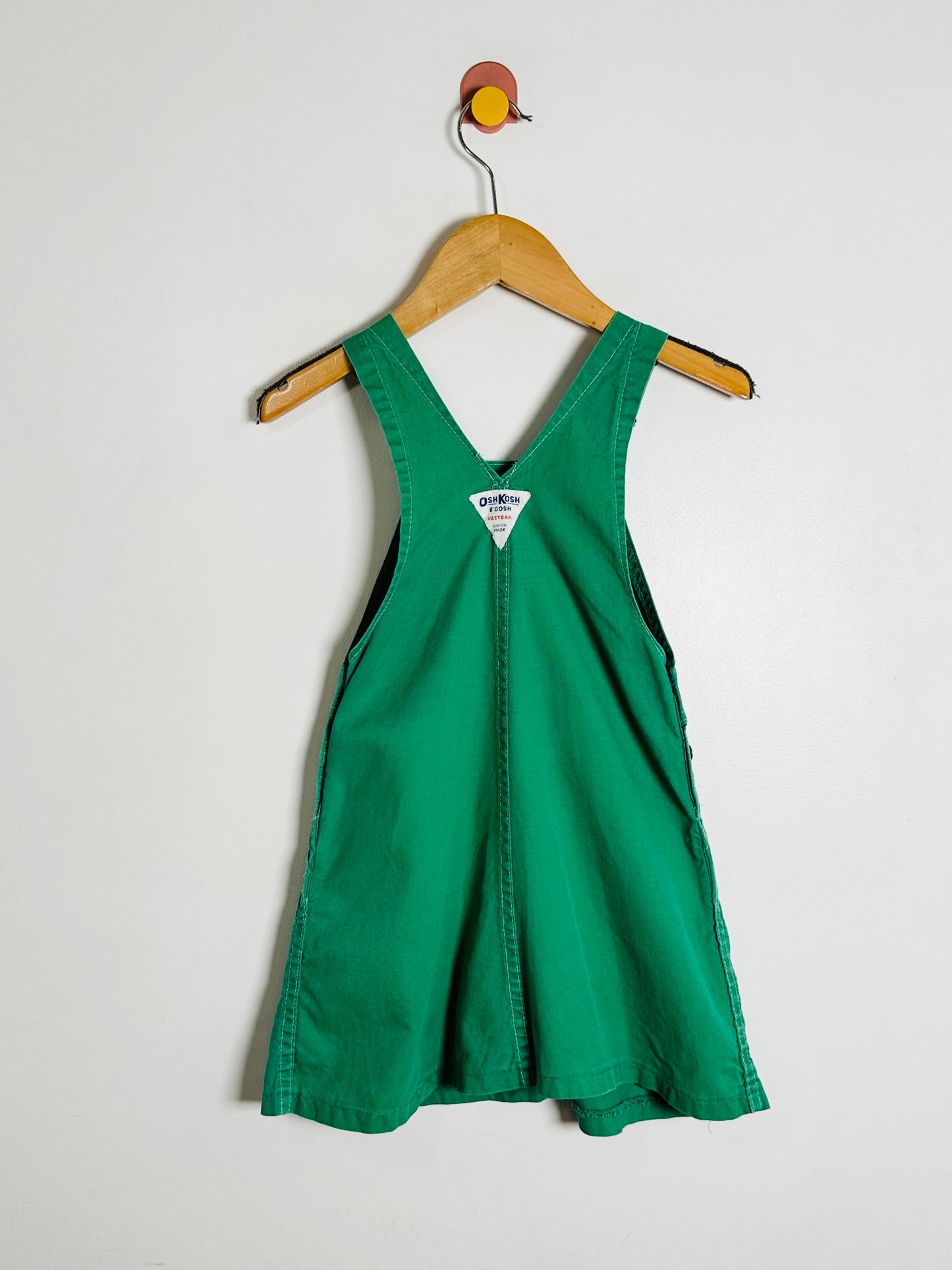 Green dress on a hanger against a white background