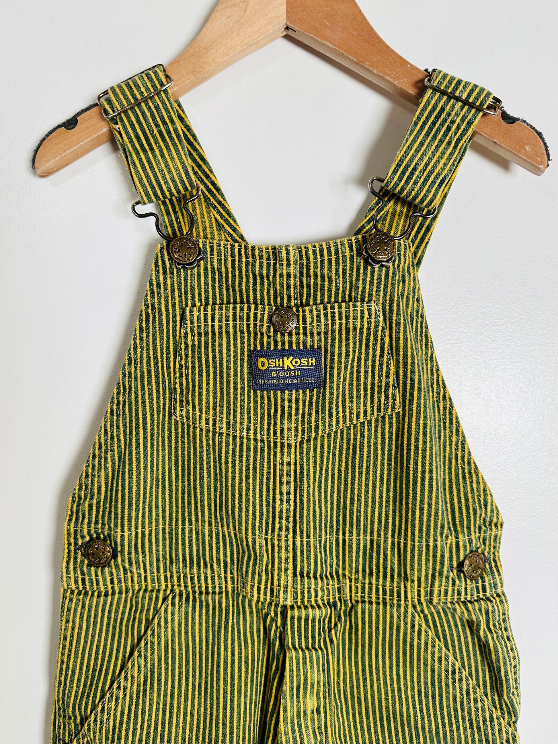 Striped overalls on a hanger with OshKosh B'gosh label.