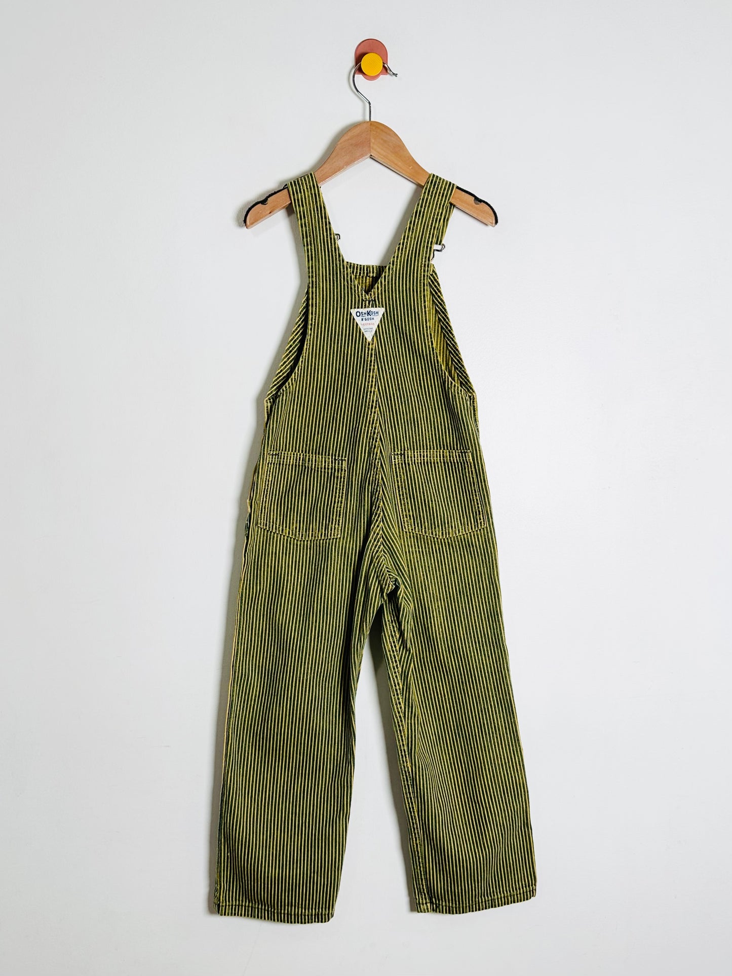 Sriped overalls hanging on a wooden hanger against a white background