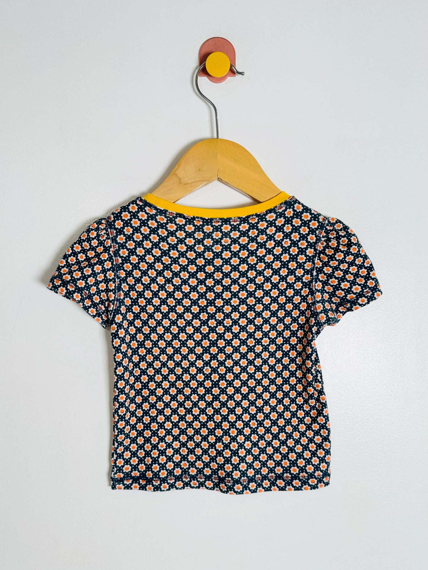 Short-sleeve shirt with floral pattern on a hanger against a white background
