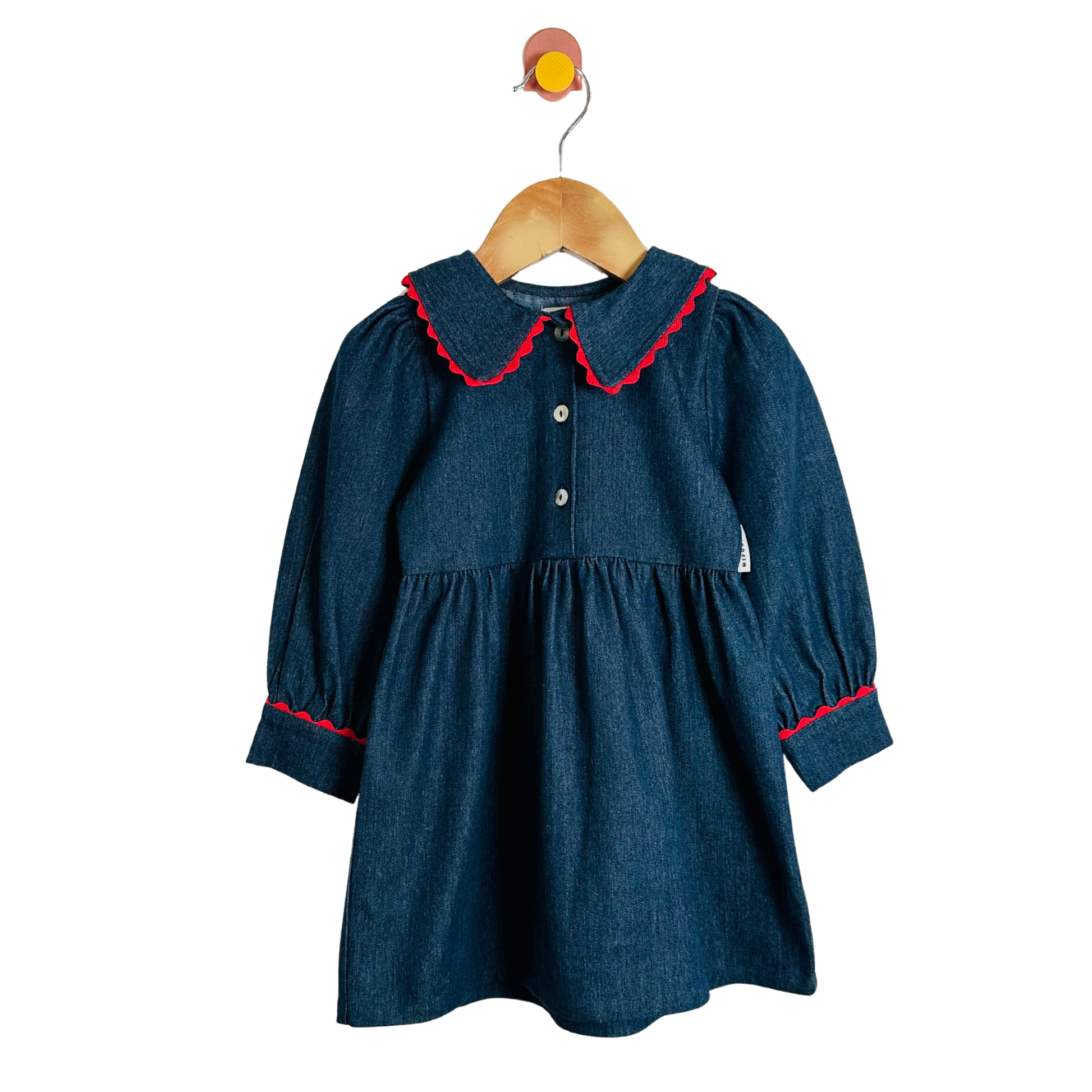 Blue dress with red trim on a wooden hanger against a white background