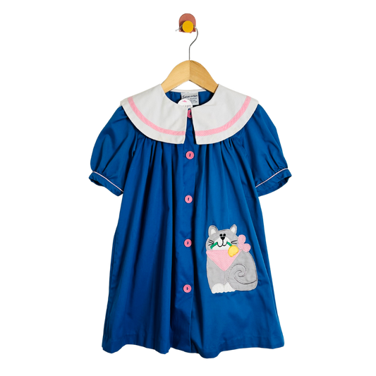 Blue dress with a cat patch on a hanger against a white background