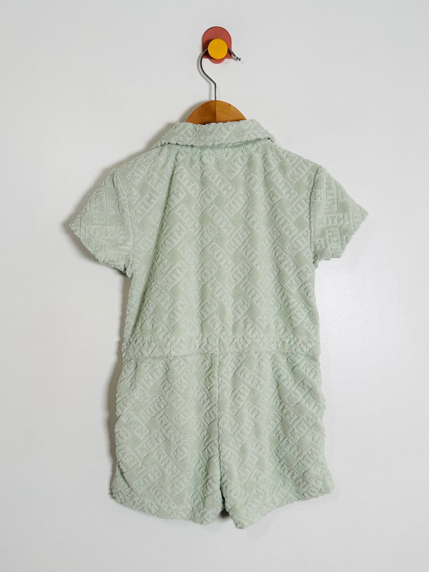 Green patterned dress on a hanger against a white background