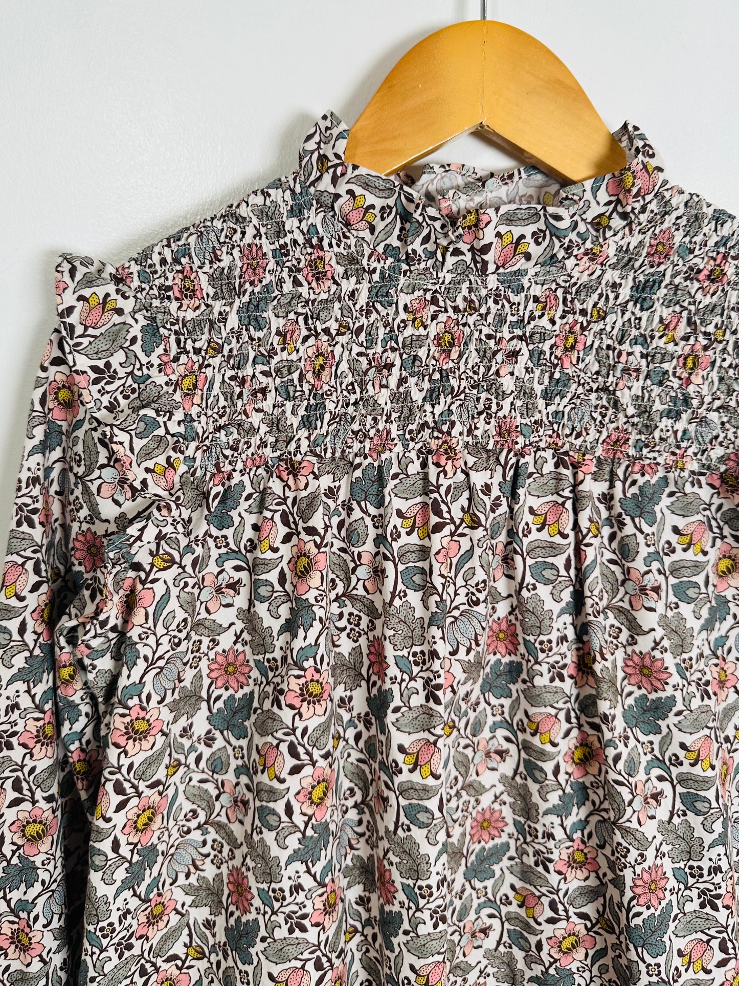 Floral patterned dress on a hanger against a white background