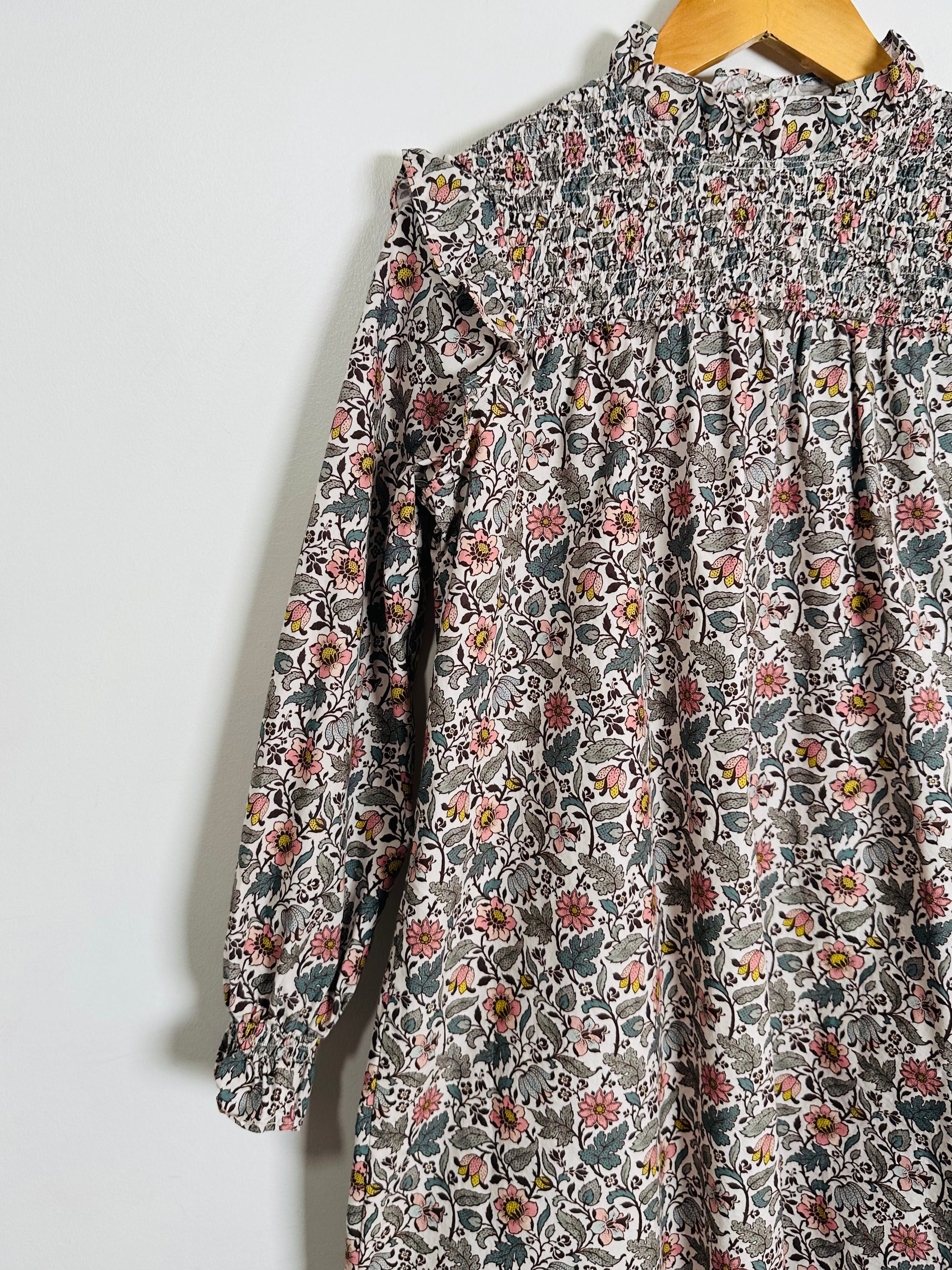 Floral patterned dress on a hanger against a white background