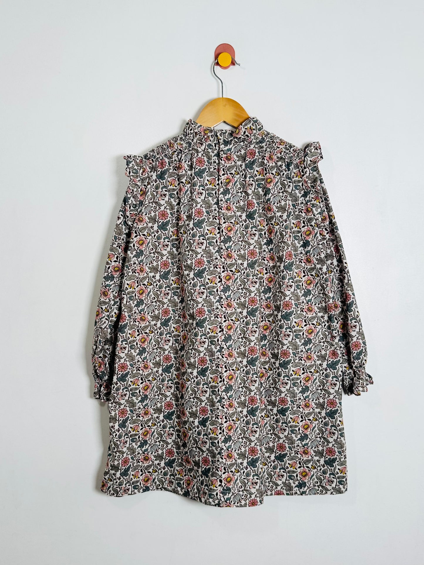 Floral patterned dress on a hanger against a white background