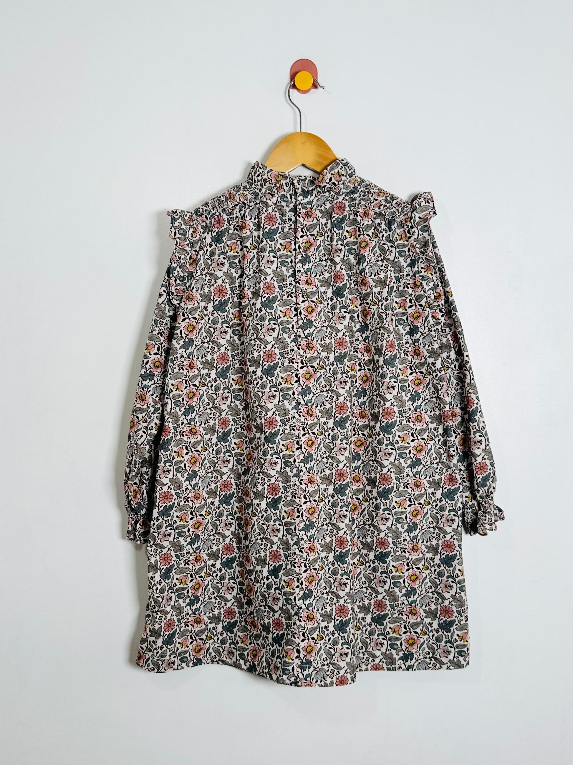 Floral patterned dress on a hanger against a white background