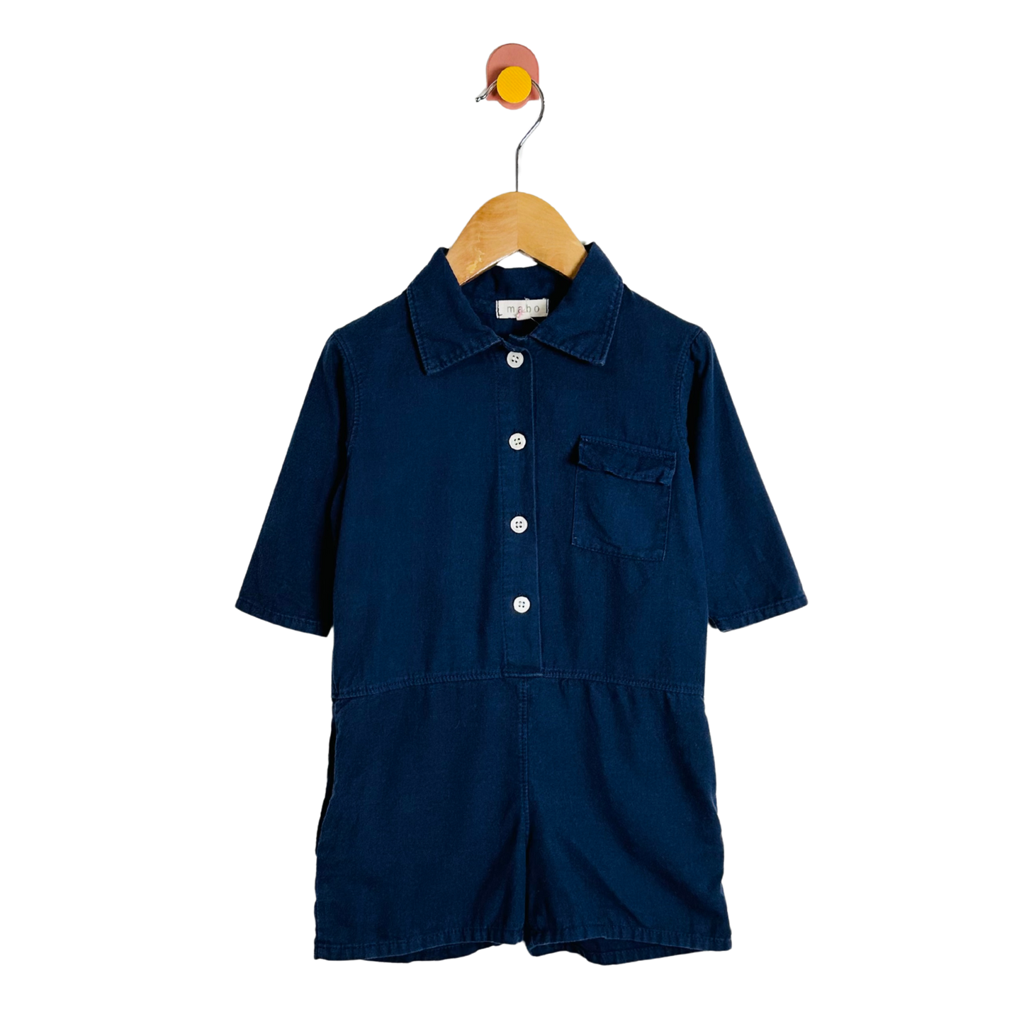 Navy blue romper on a wooden hanger against a white background