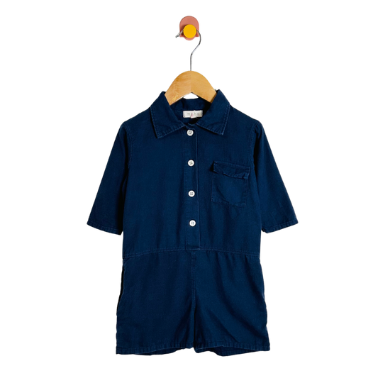 Navy blue romper on a wooden hanger against a white background