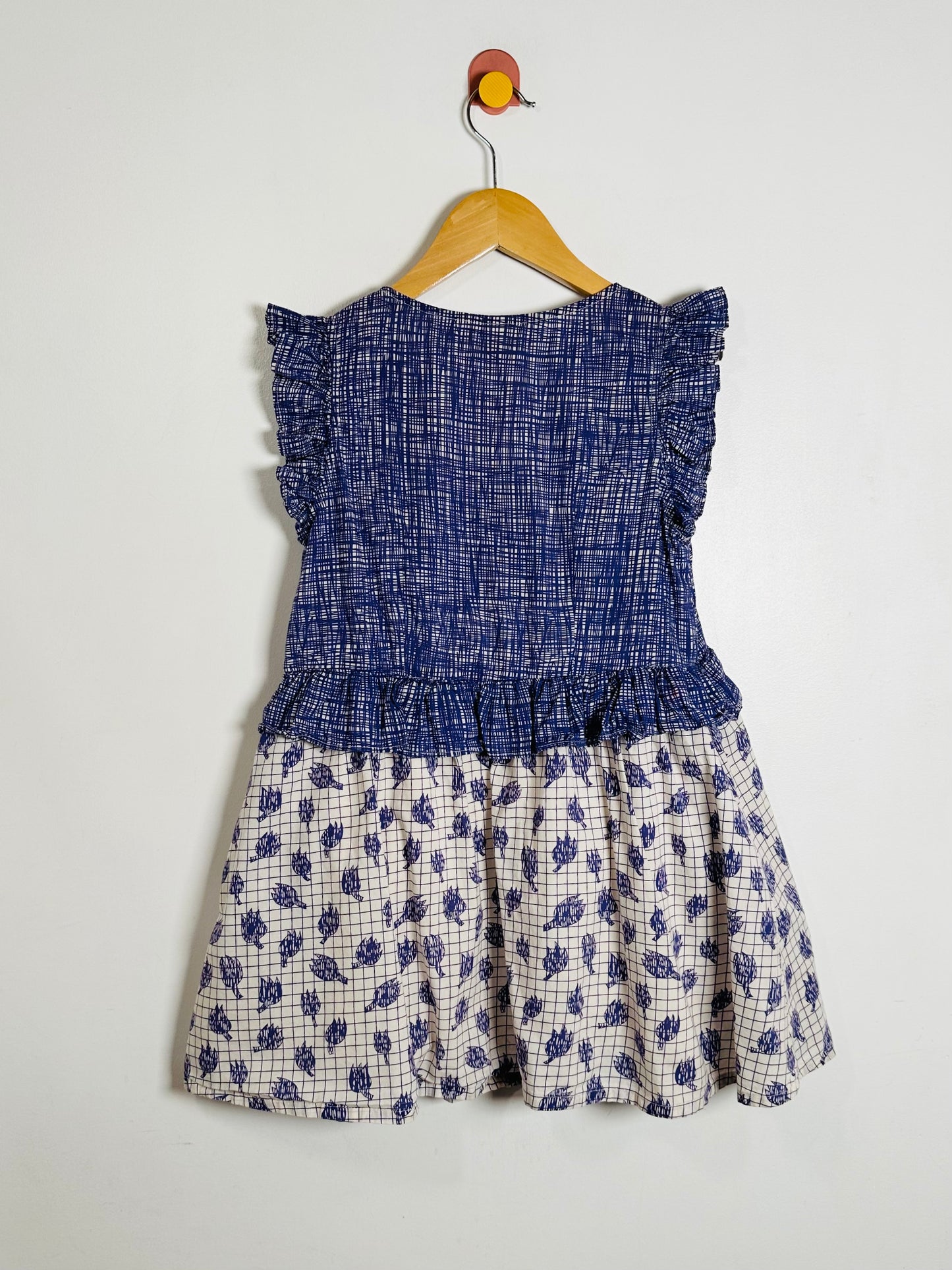 Children's dress with blue top and floral skirt on a hanger against a white background