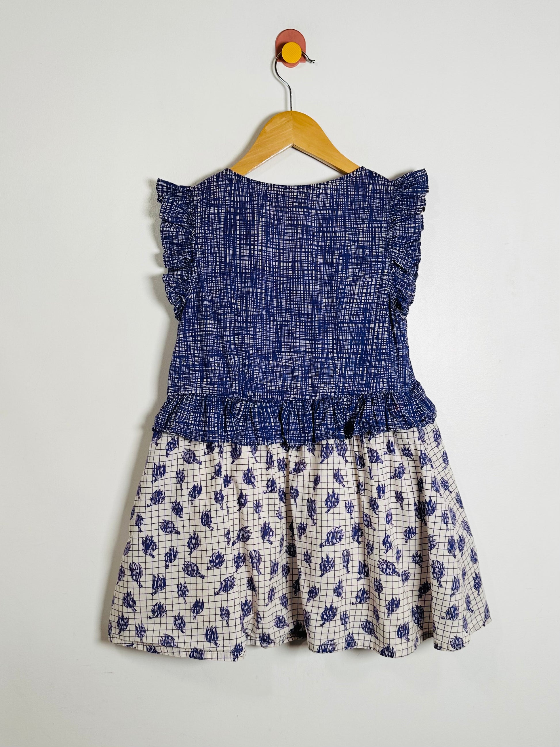 Children's dress with blue top and floral skirt on a hanger against a white background