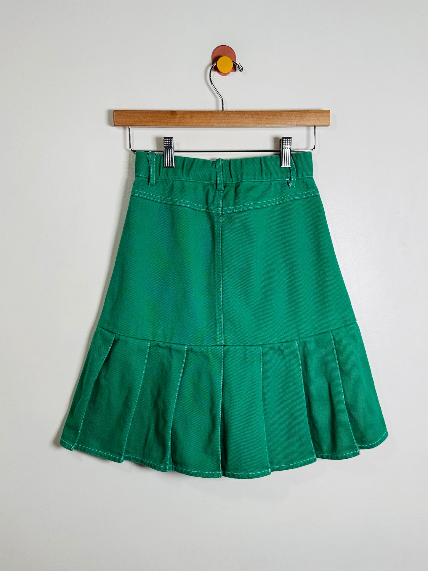Green skirt on a hanger against a white background