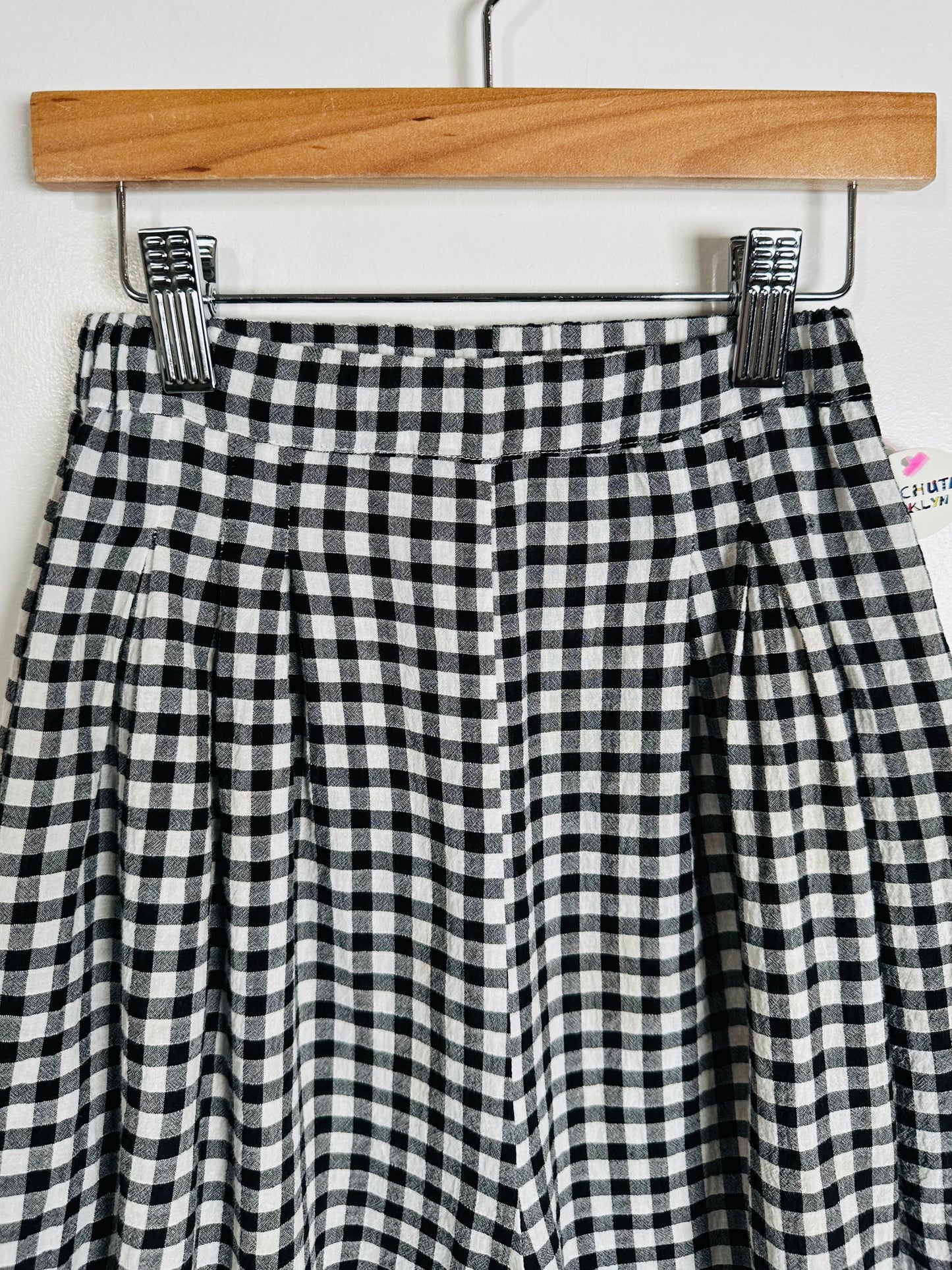 Black and white checkered skirt on a wooden hanger against a white background
