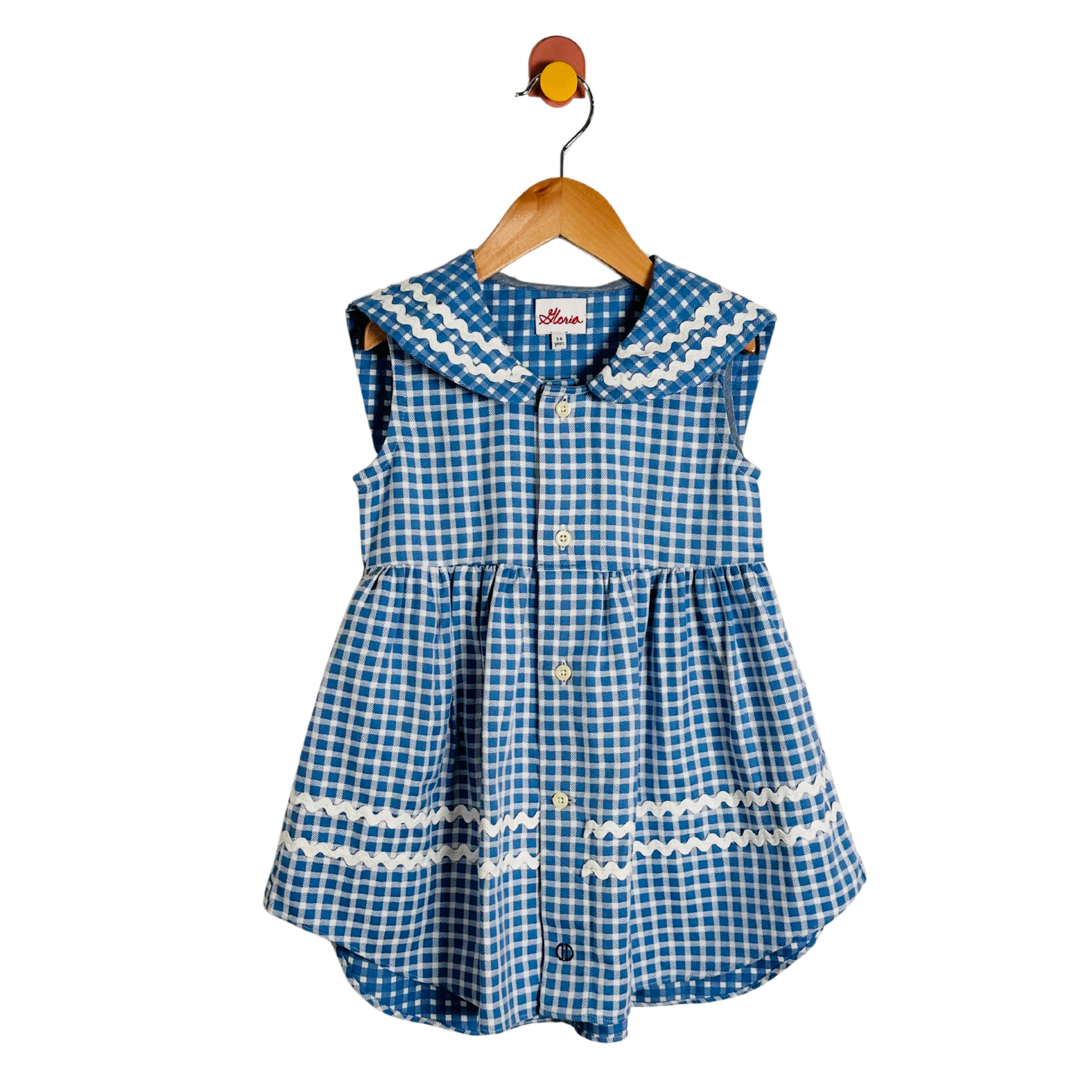 Blue checkered dress with white trim on a wooden hanger against a white background