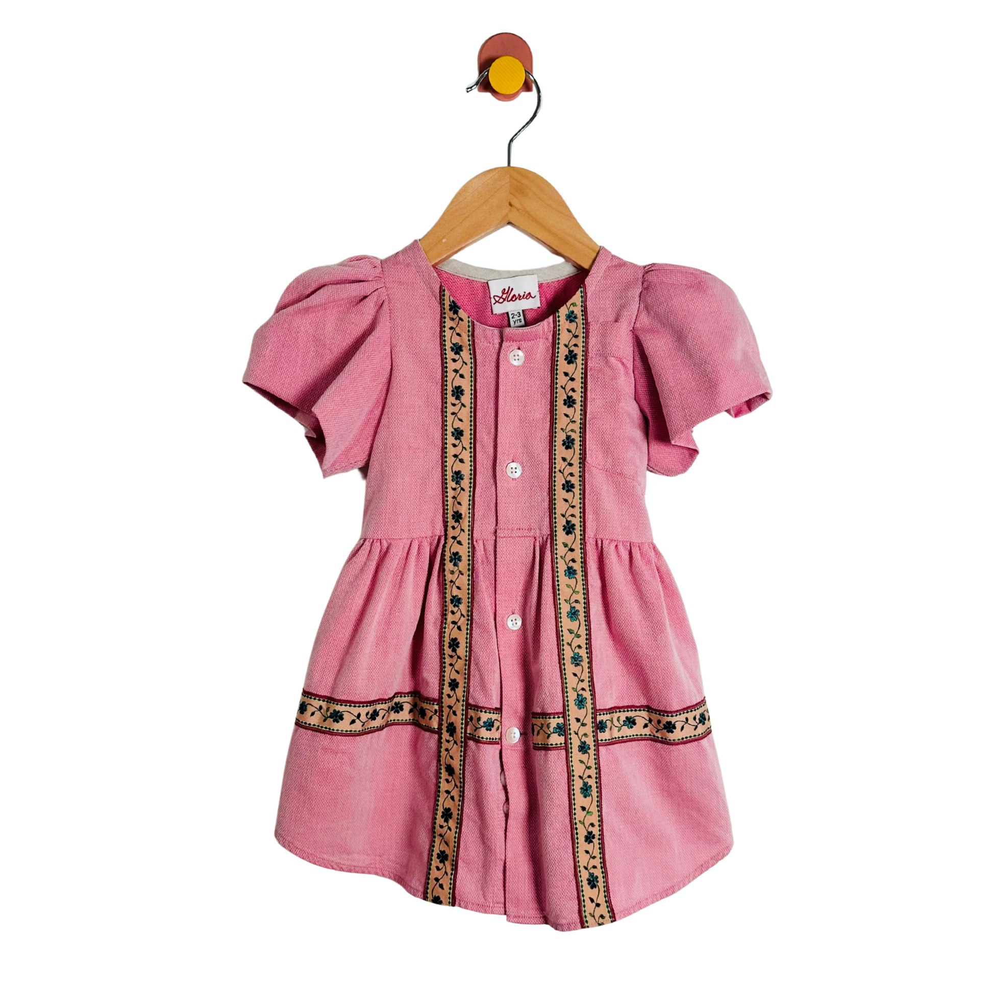 Pink dress with decorative elements on a hanger against a white background