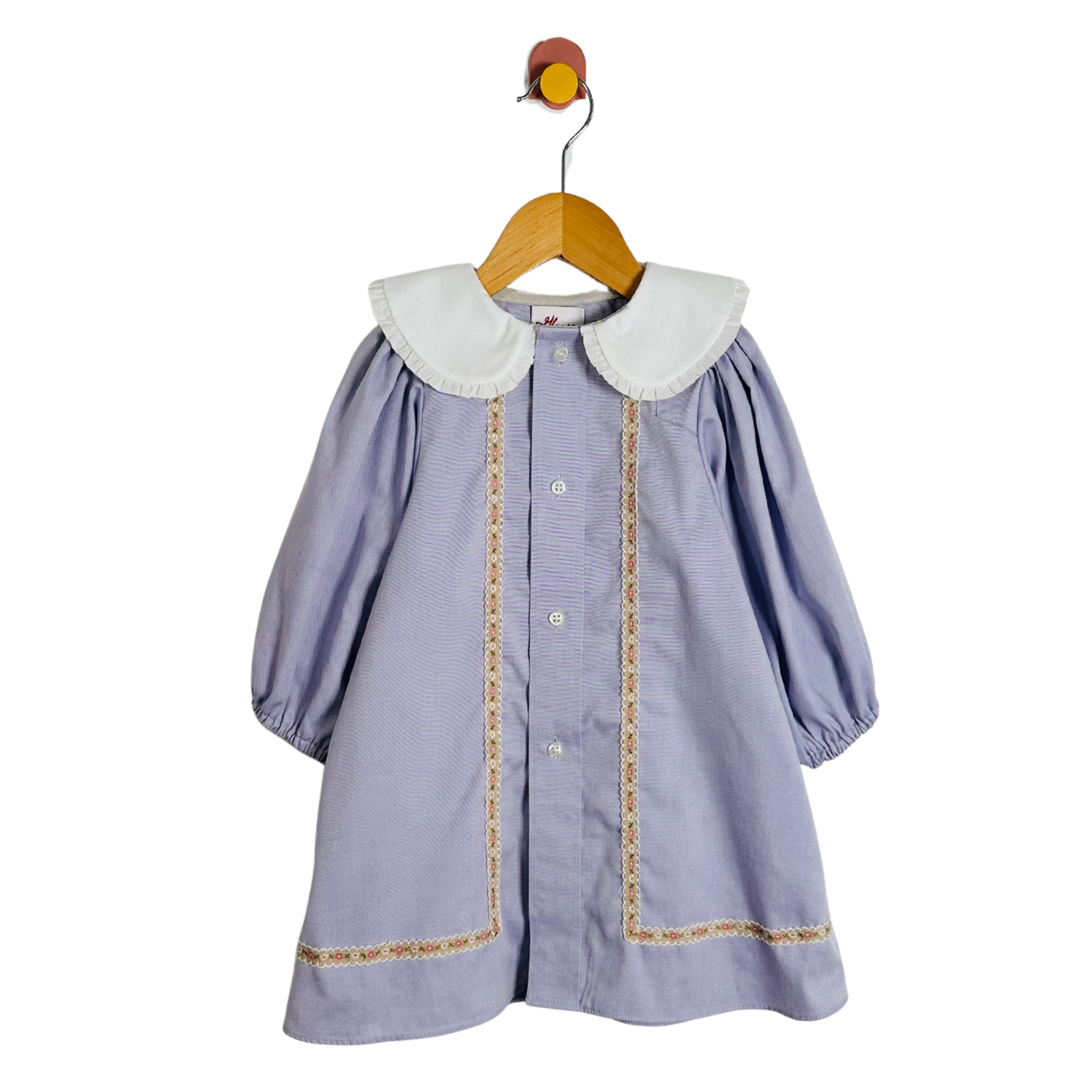 Children's dress with white collar and trim on a wooden hanger against a white background