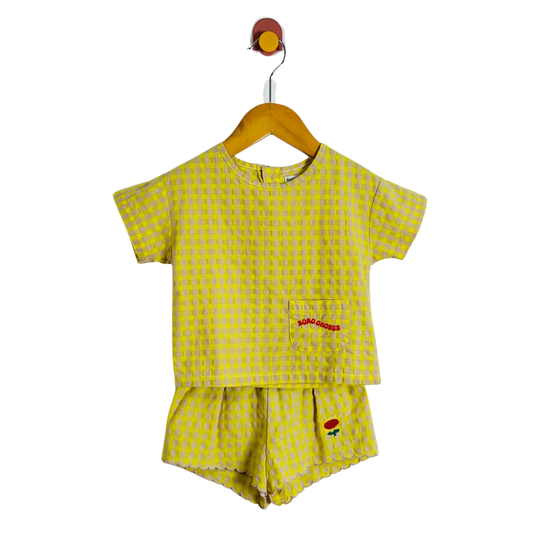 Yellow checkered children's outfit with a top and shorts on a hanger against a white background.