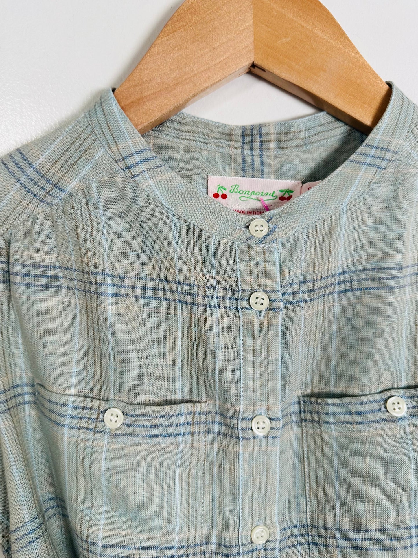 Plaid dress with buttons on a hanger against a white background