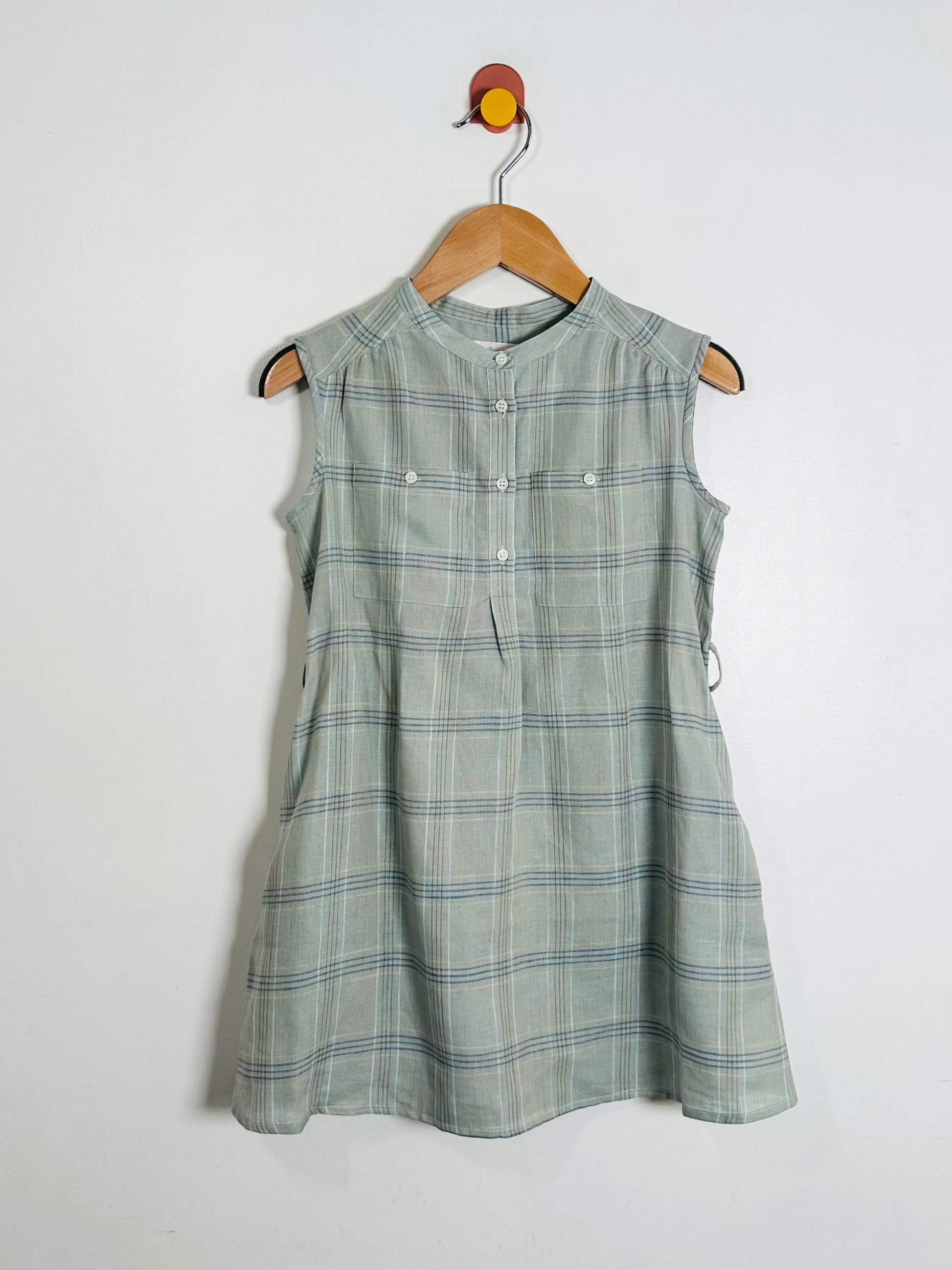 Green plaid dress on a hanger against a white background