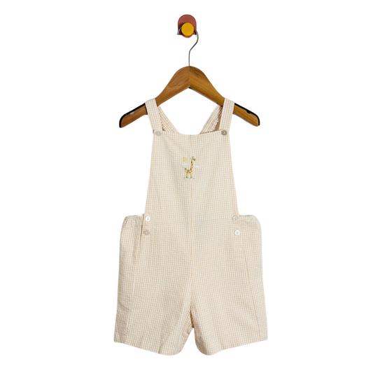 Beige checkered overalls hanging on a wooden hanger against a white background