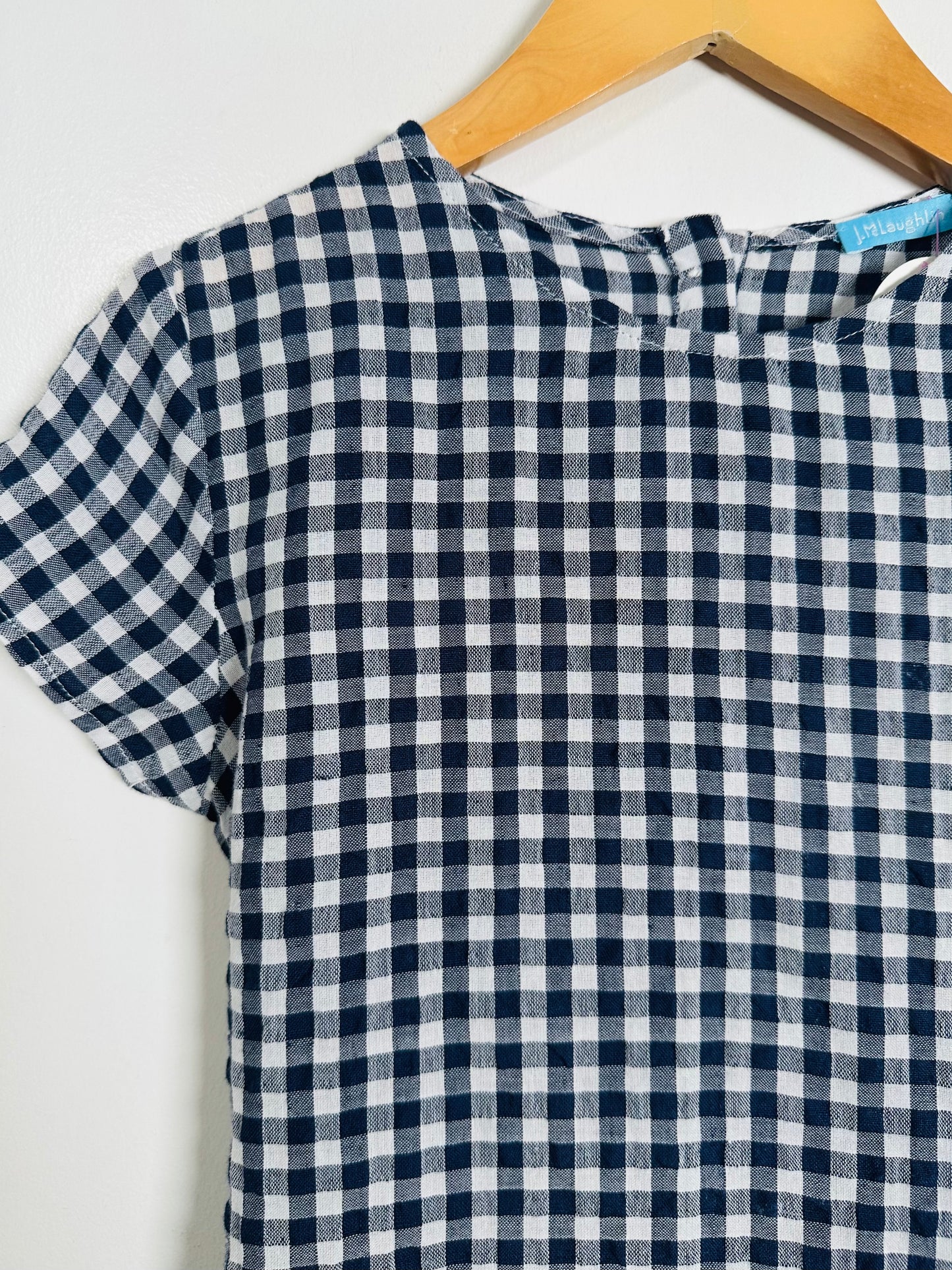 Navy and white checkered shirt on a hanger against a white background