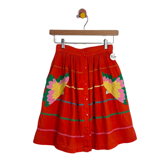 Red skirt with floral patterns on a hanger against a white background