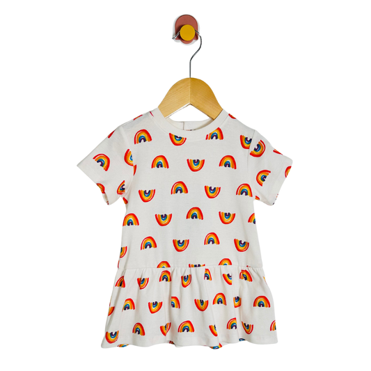 White dress with rainbow pattern on a wooden hanger against a white background