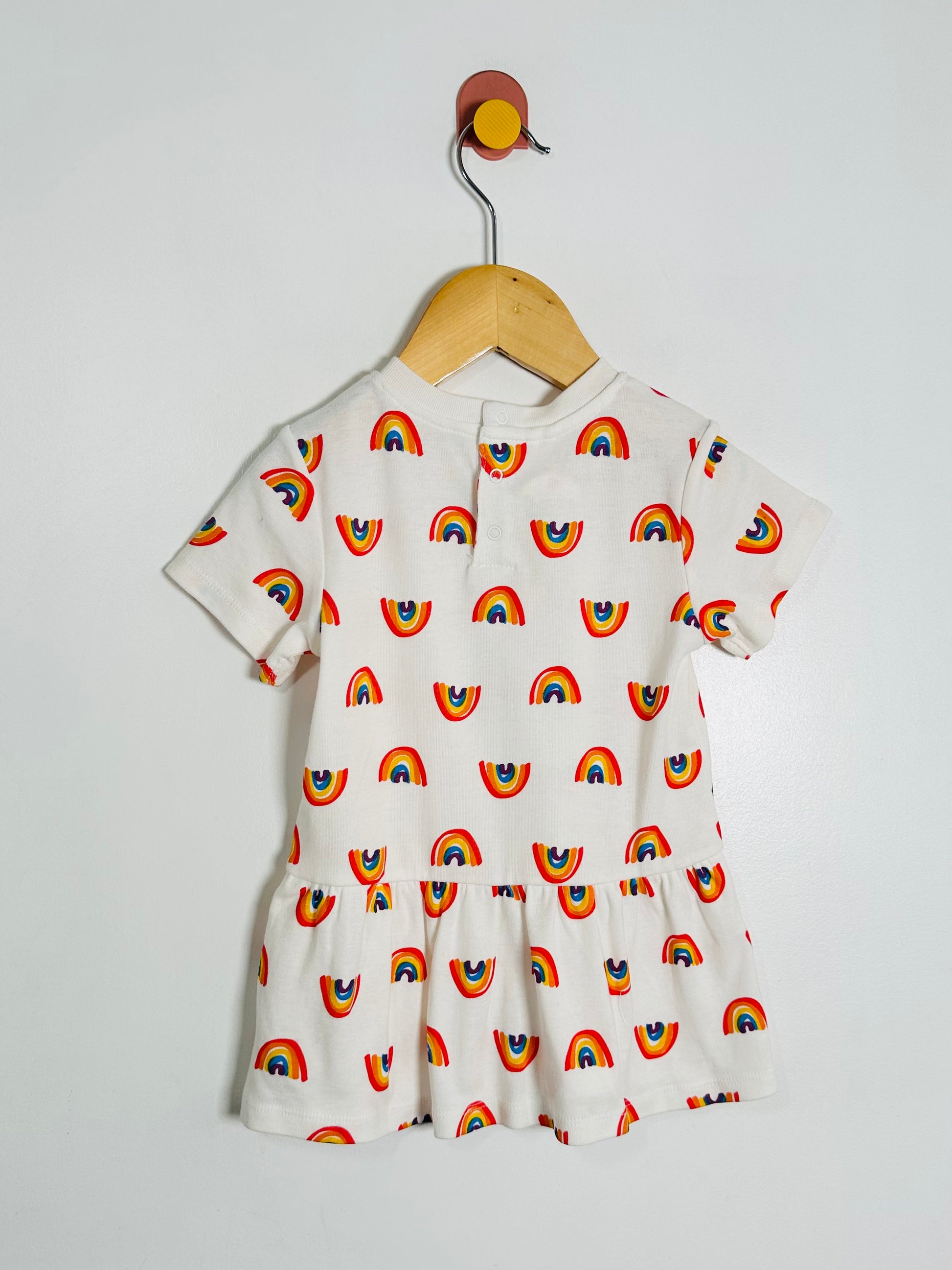 White dress with rainbow pattern on a hanger against a white background