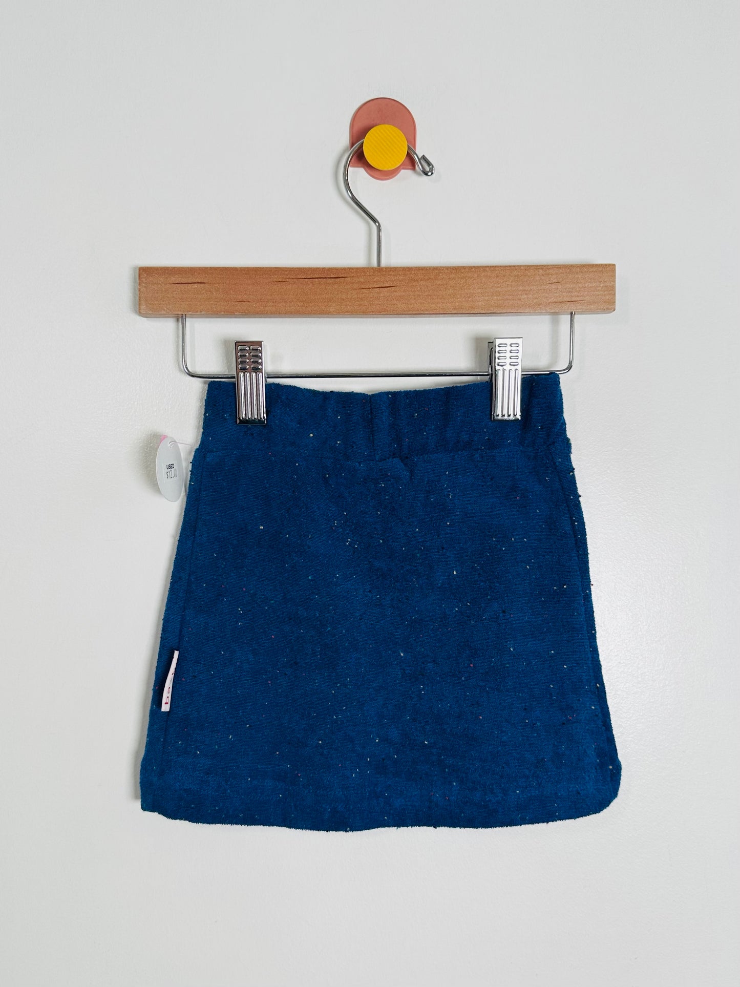 Blue skirt on a wooden hanger against a white background