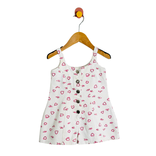 White dress with pink heart pattern on a wooden hanger against a white background