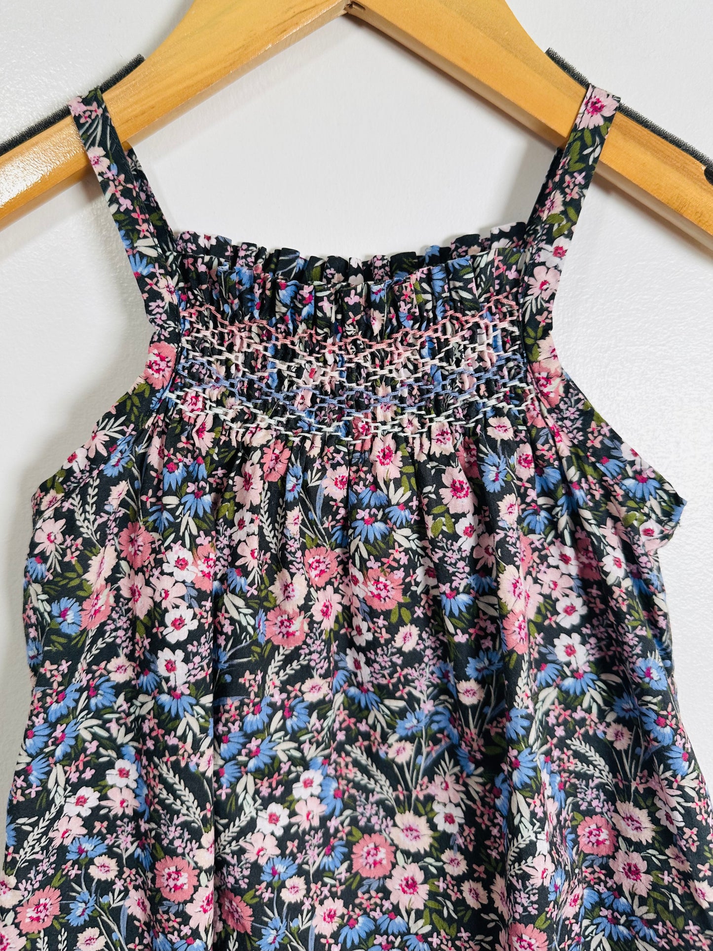 Floral romper on a wooden hanger against a white background