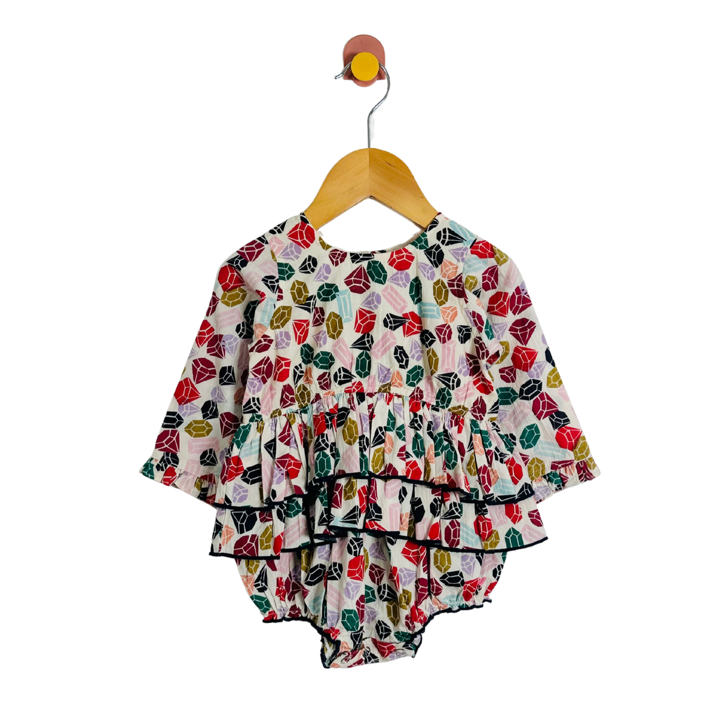 Colorful gemstone-patterned baby outfit on a hanger against a white background