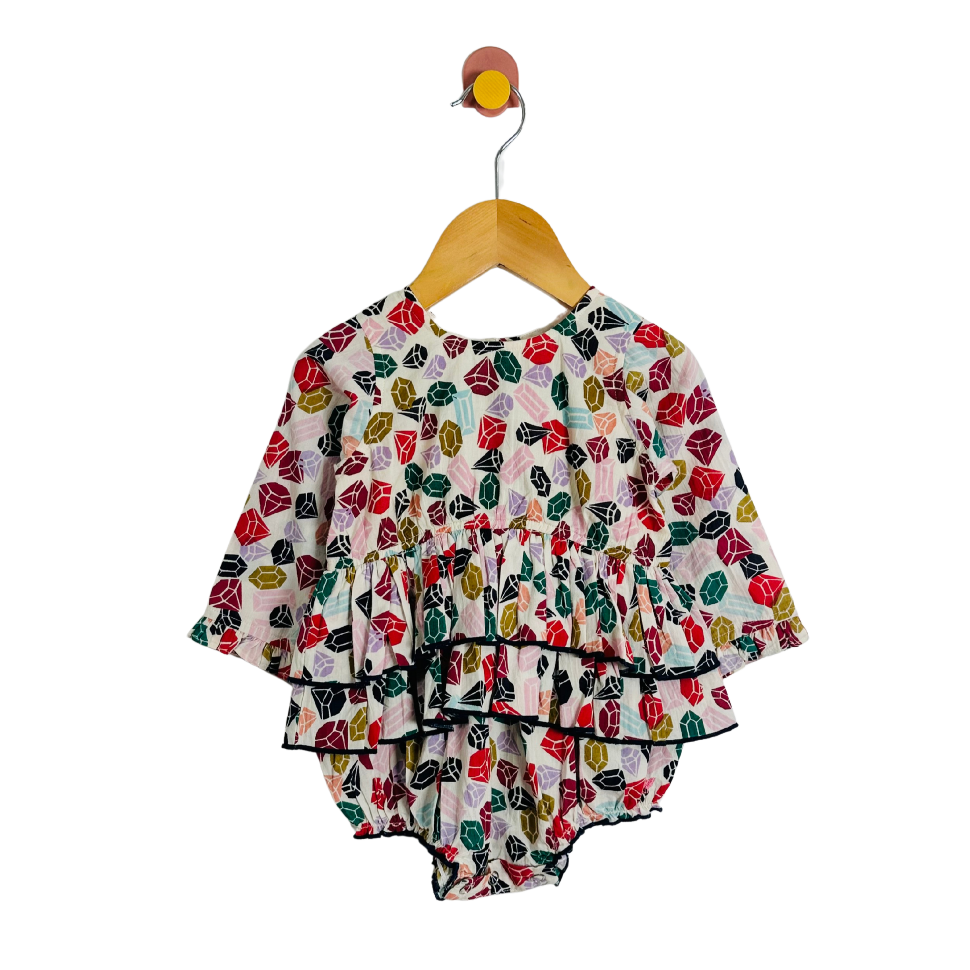 Colorful gemstone-patterned baby outfit on a hanger against a white background