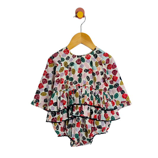 Colorful gemstone-patterned baby outfit on a hanger against a white background