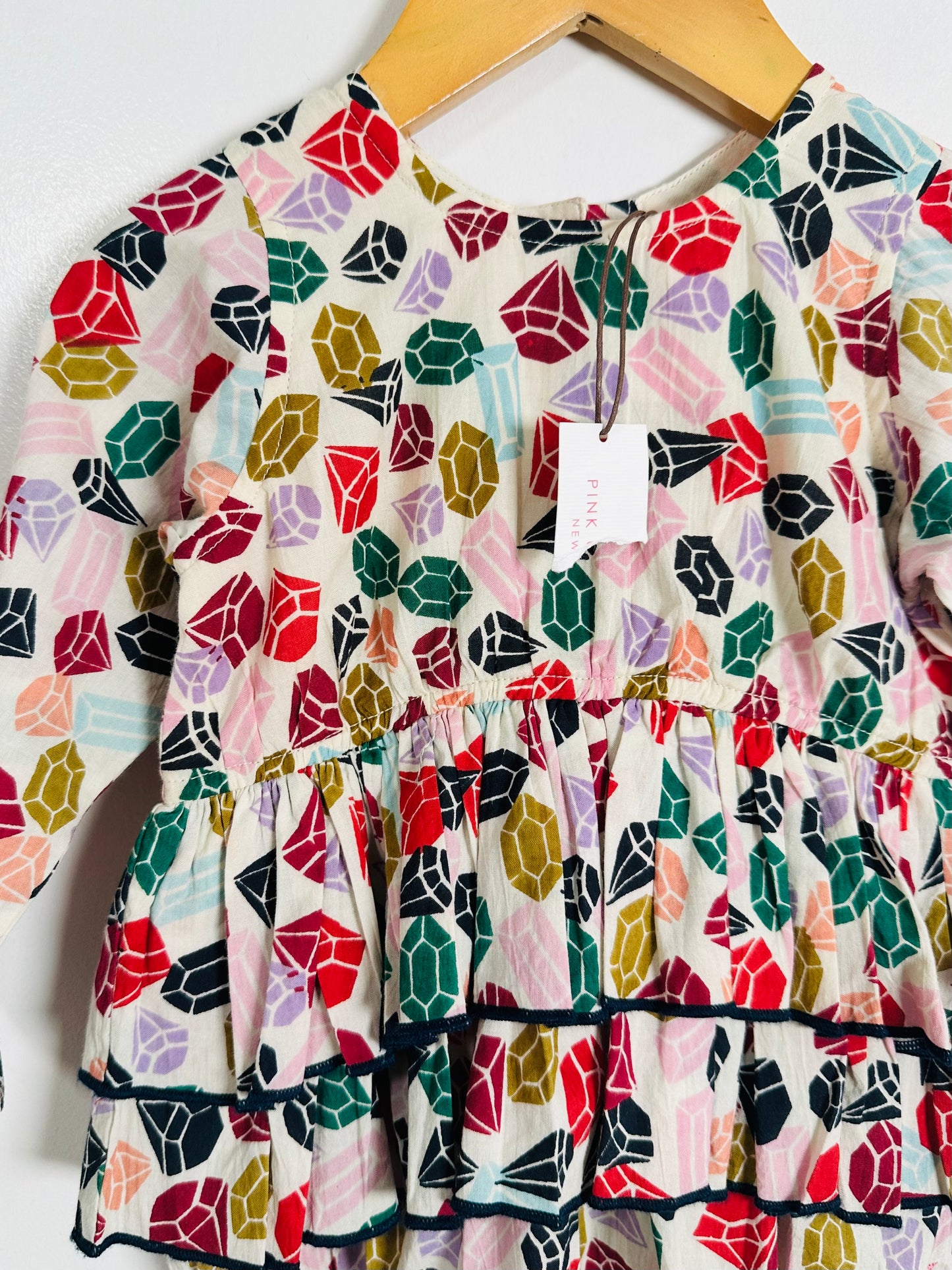 Colorful geometric patterned dress on a hanger against a white background