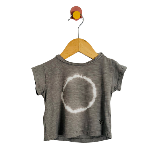 Gray t-shirt with a white circle design on a wooden hanger against a white background