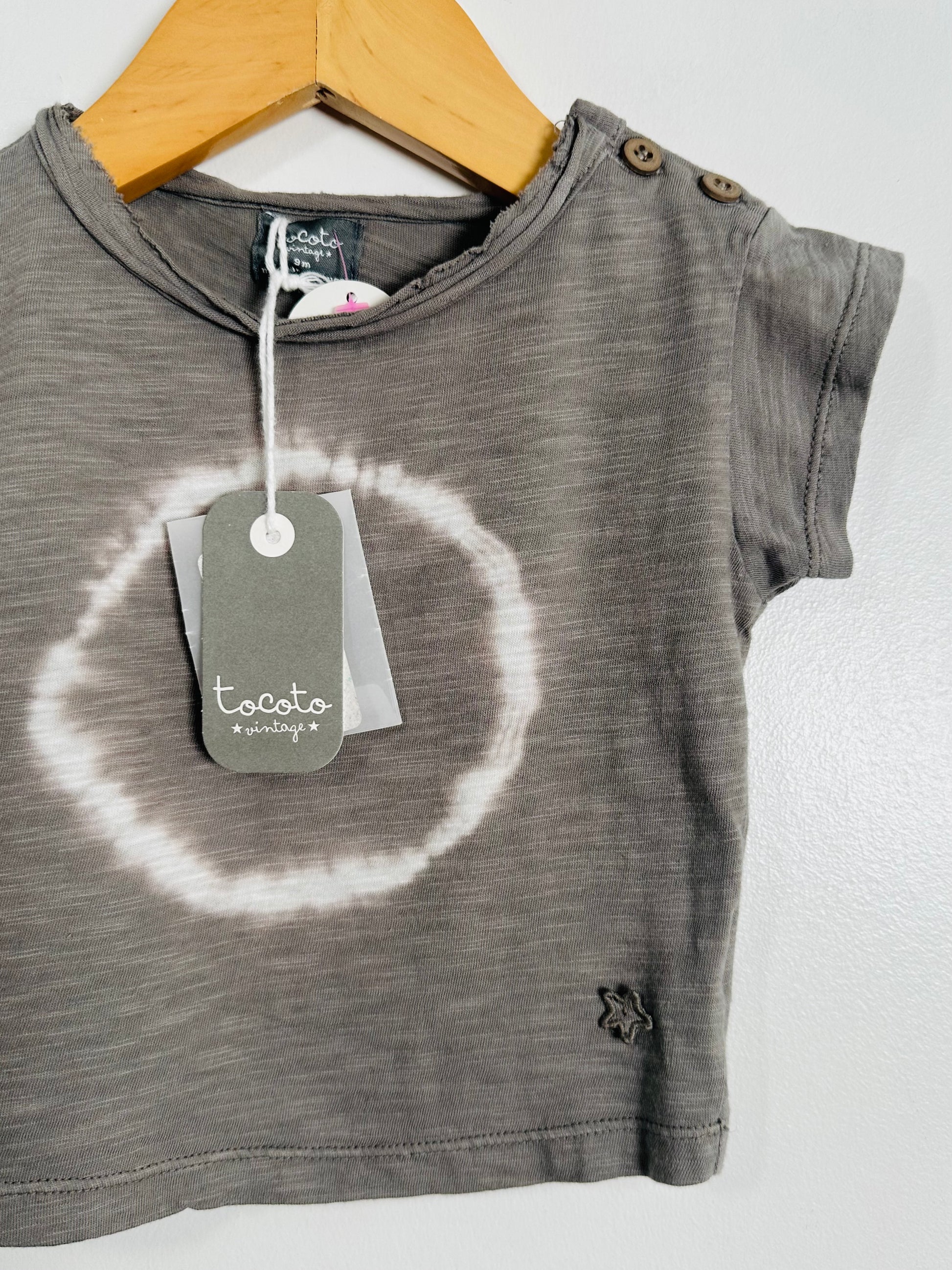Gray children's t-shirt with a tag on a wooden hanger against a white background