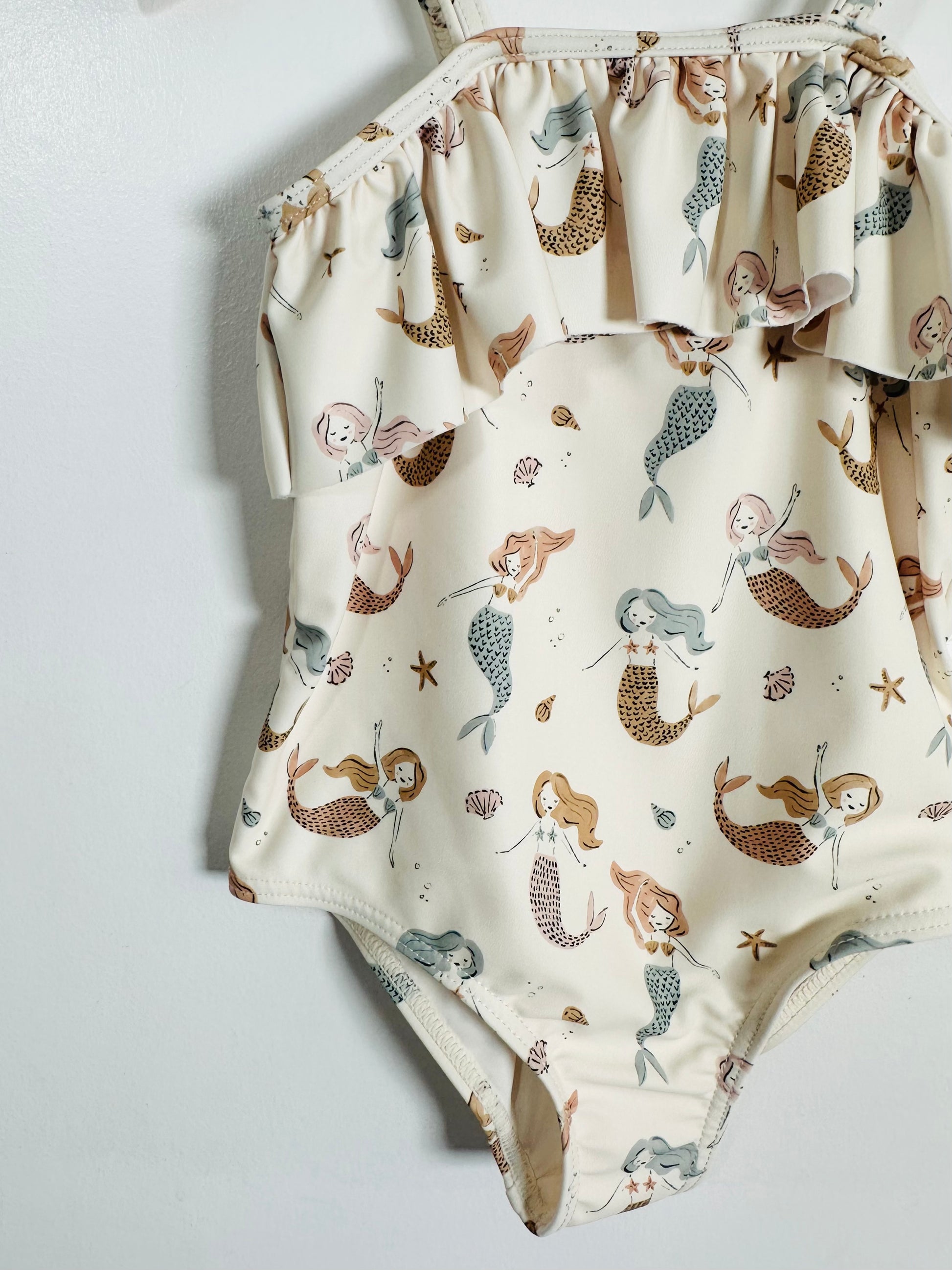 Children's swimsuit with mermaid pattern on a light gray background