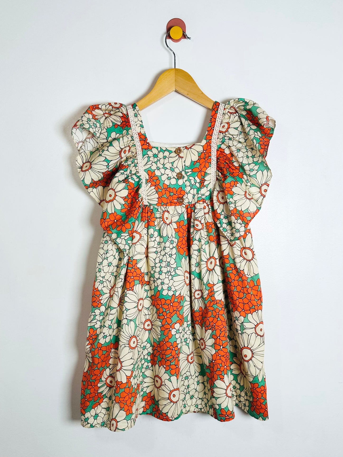 Floral dress with ruffled sleeves on a hanger against a white background