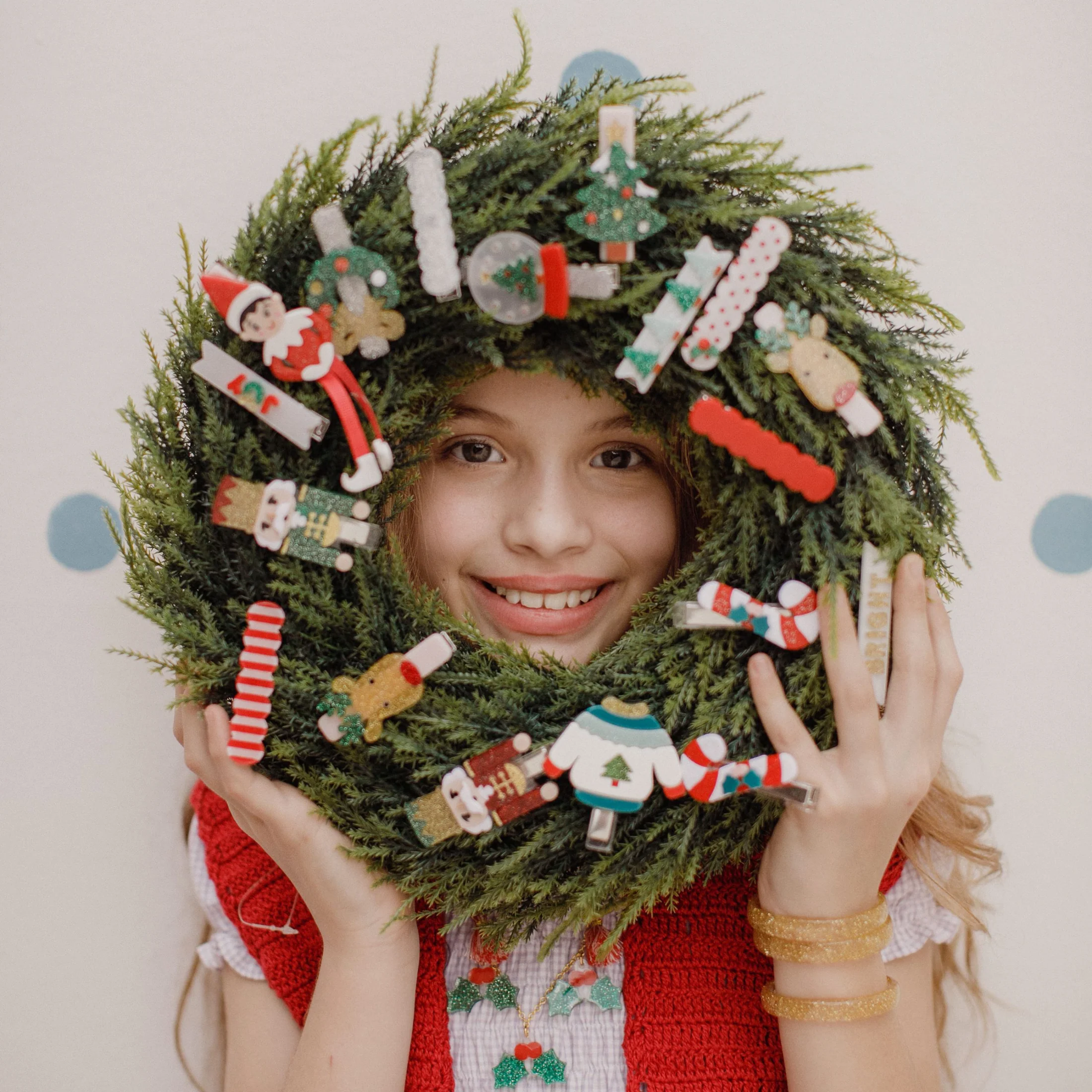Child wearing a festive wreath with Christmas decorations on a light background