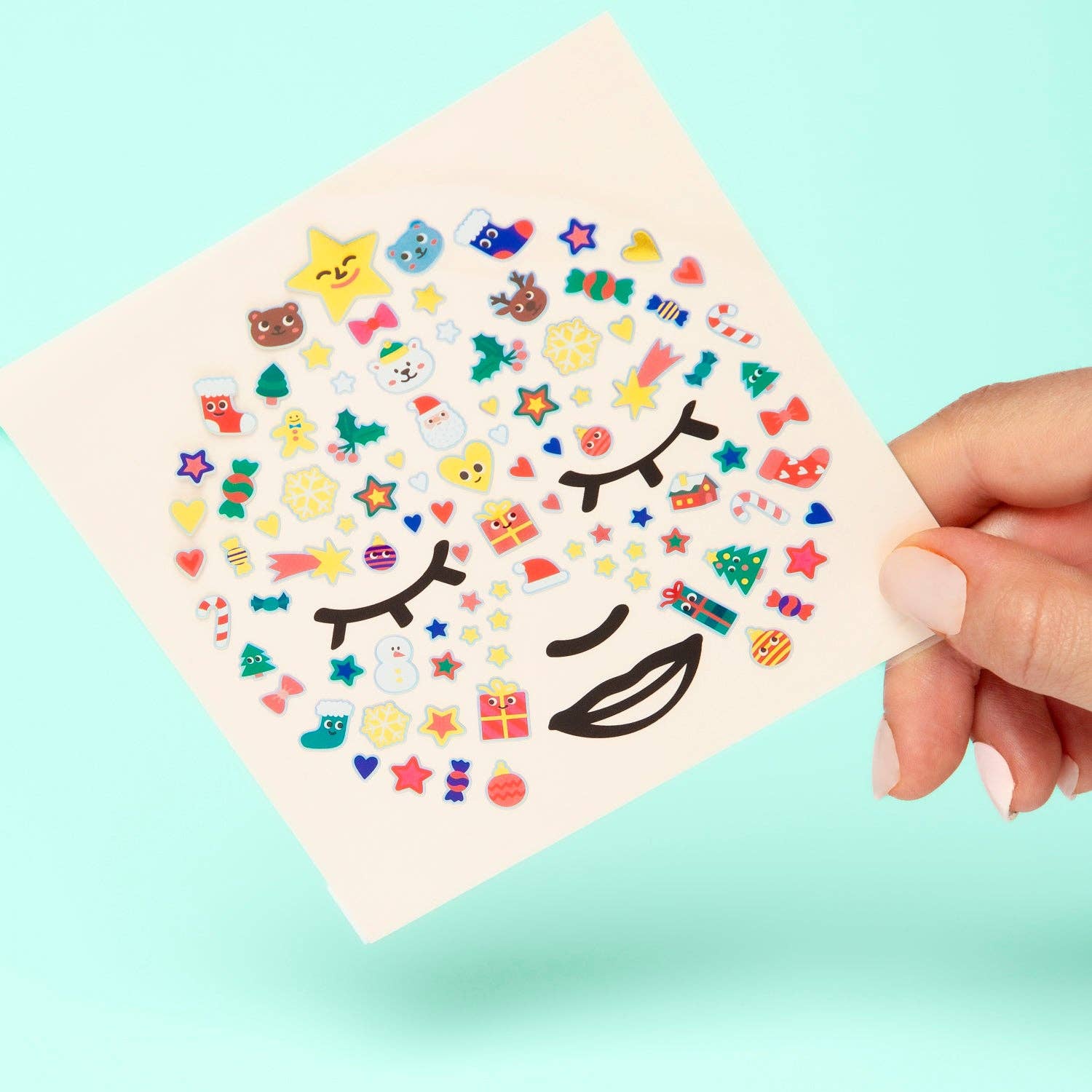 Sheet of colorful face stickers with various designs held by a hand against a light blue background