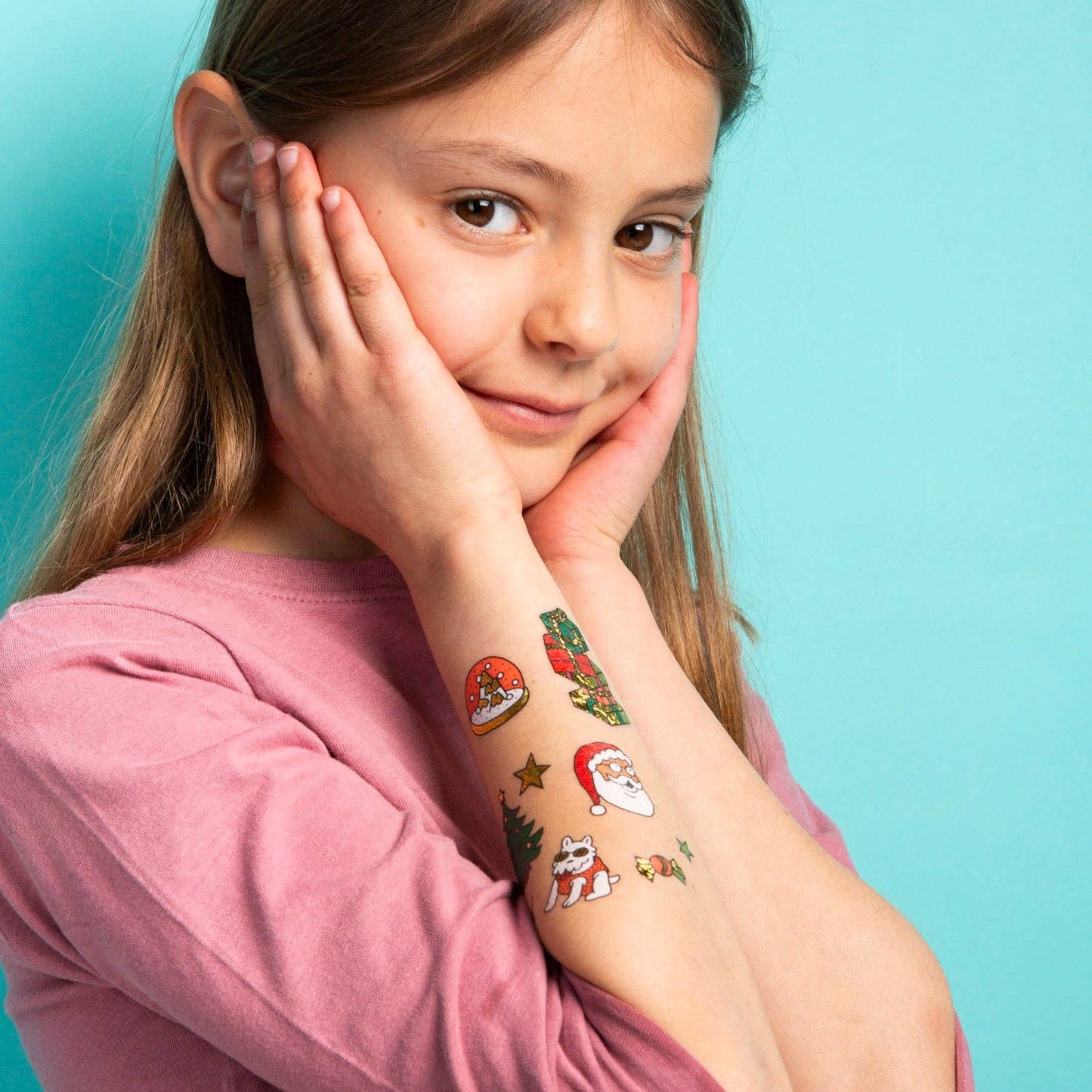 Girl with colorful temporary tattoos on her arm against a light blue background