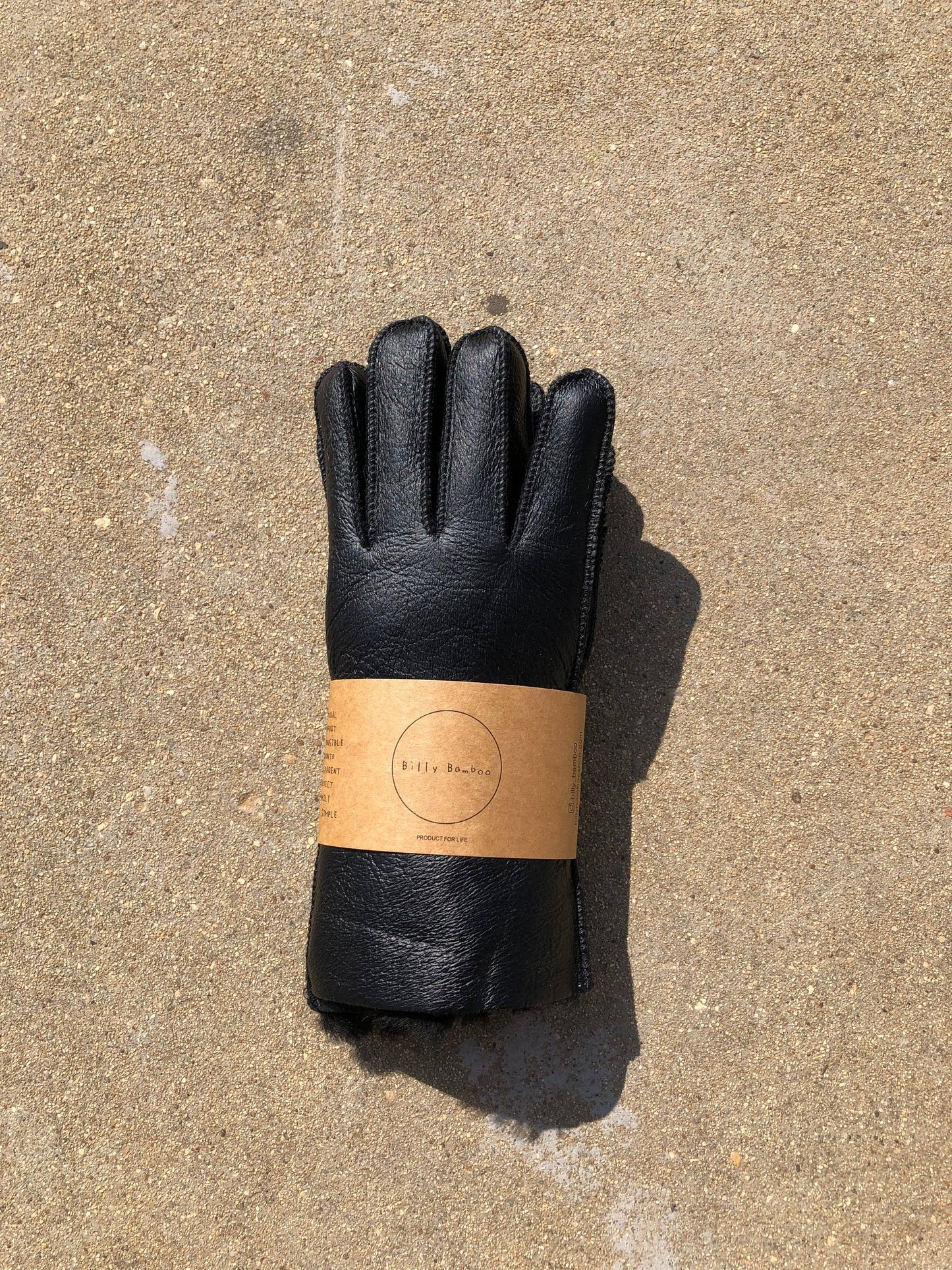 Black leather glove with a brown label on a concrete surface