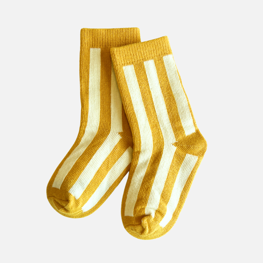 Pair of yellow socks with white stripes on a light gray background