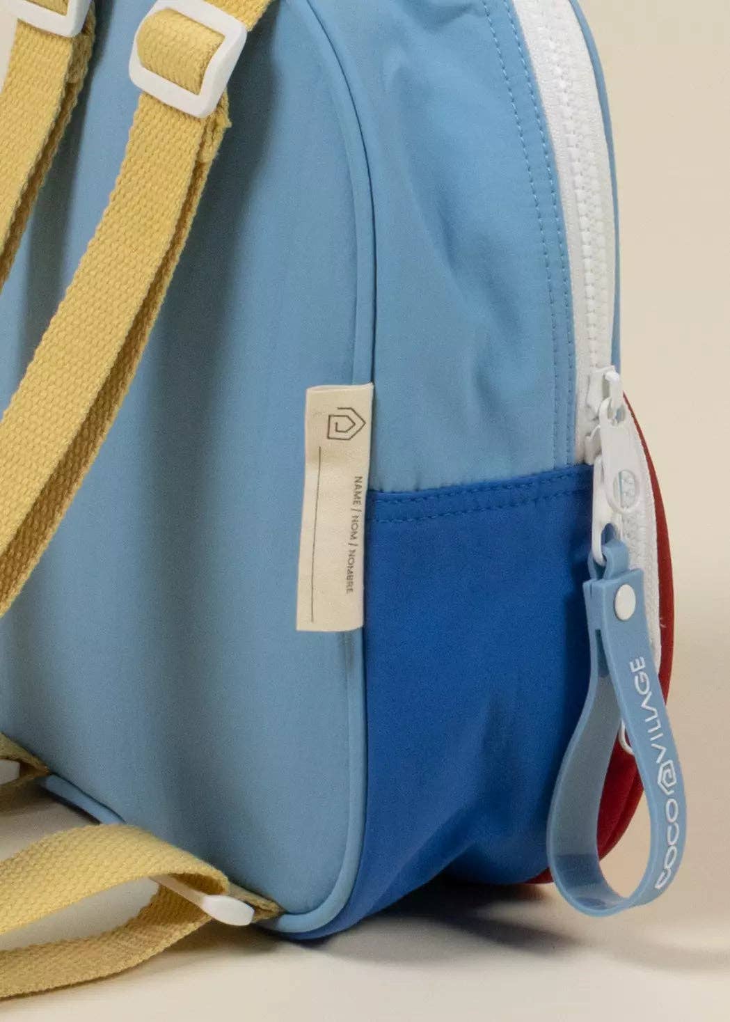 Blue bag with a yellow strap and visible brand tag on a beige background
