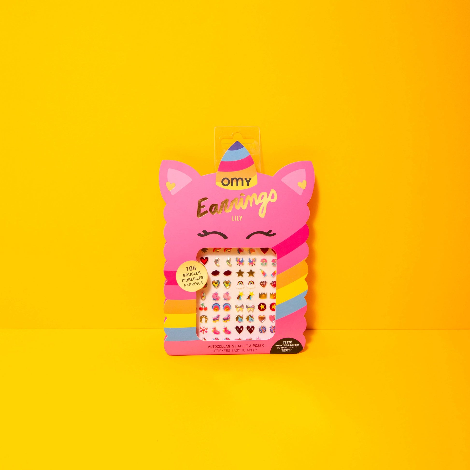 Pink packaging of OMY earrings on a yellow background