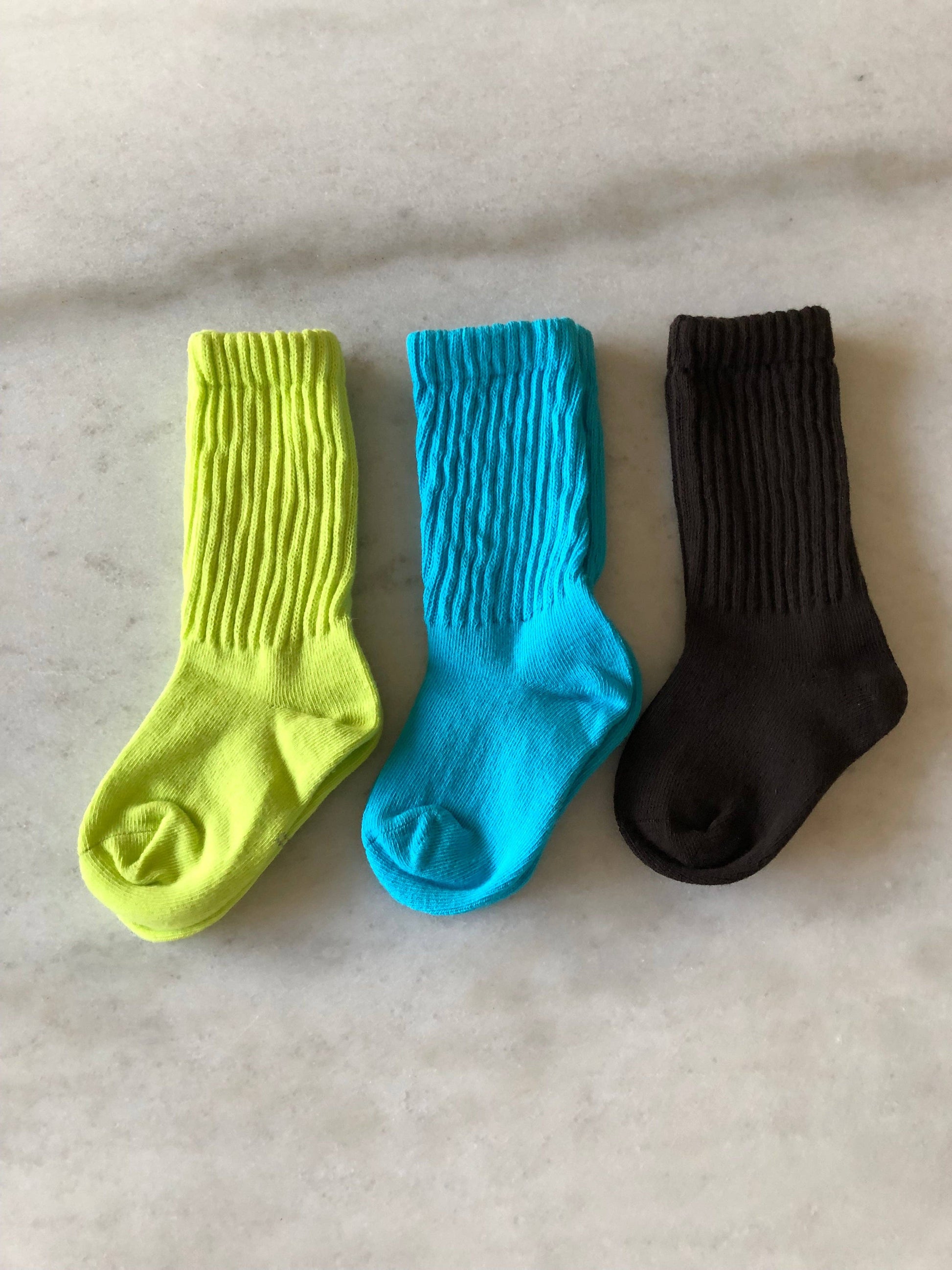 Three socks in yellow, blue, and black on a light gray surface